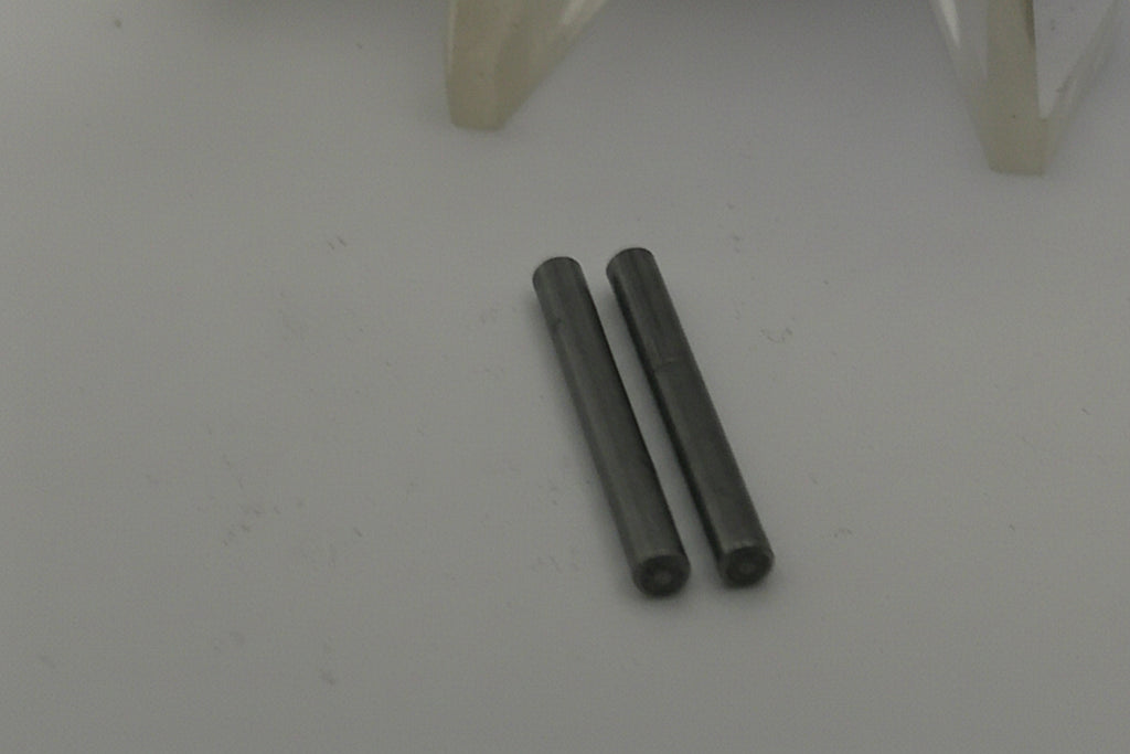 Two metallic pins on a white surface