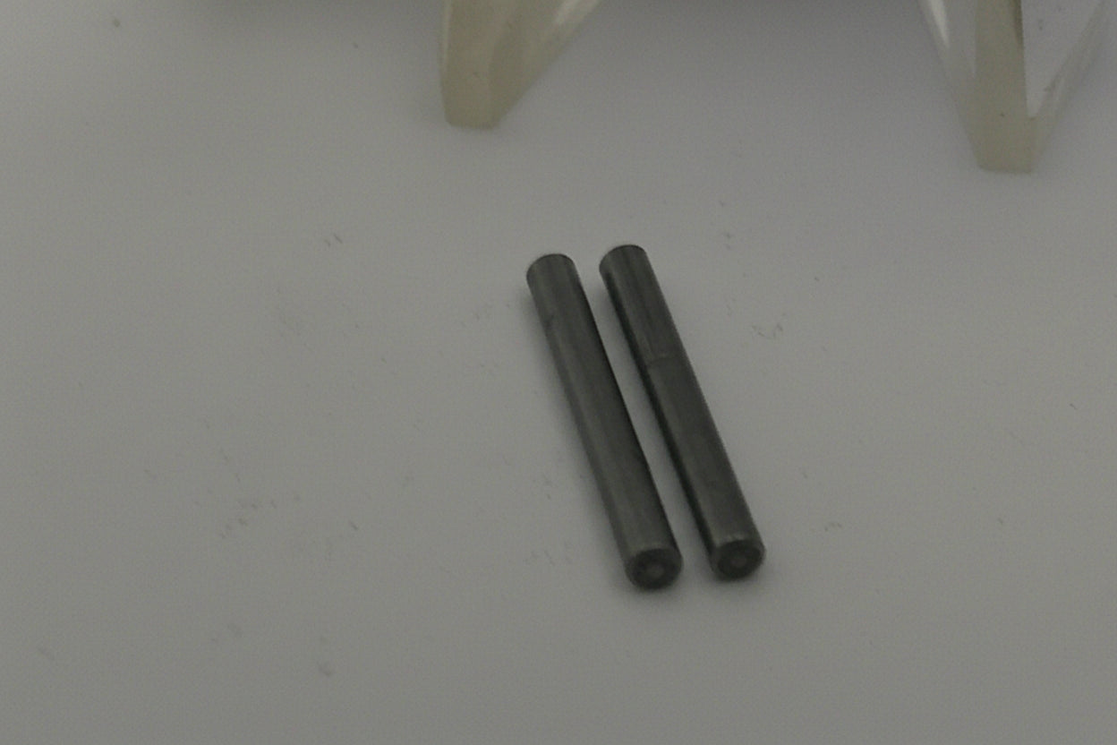 Two metallic pins on a white surface