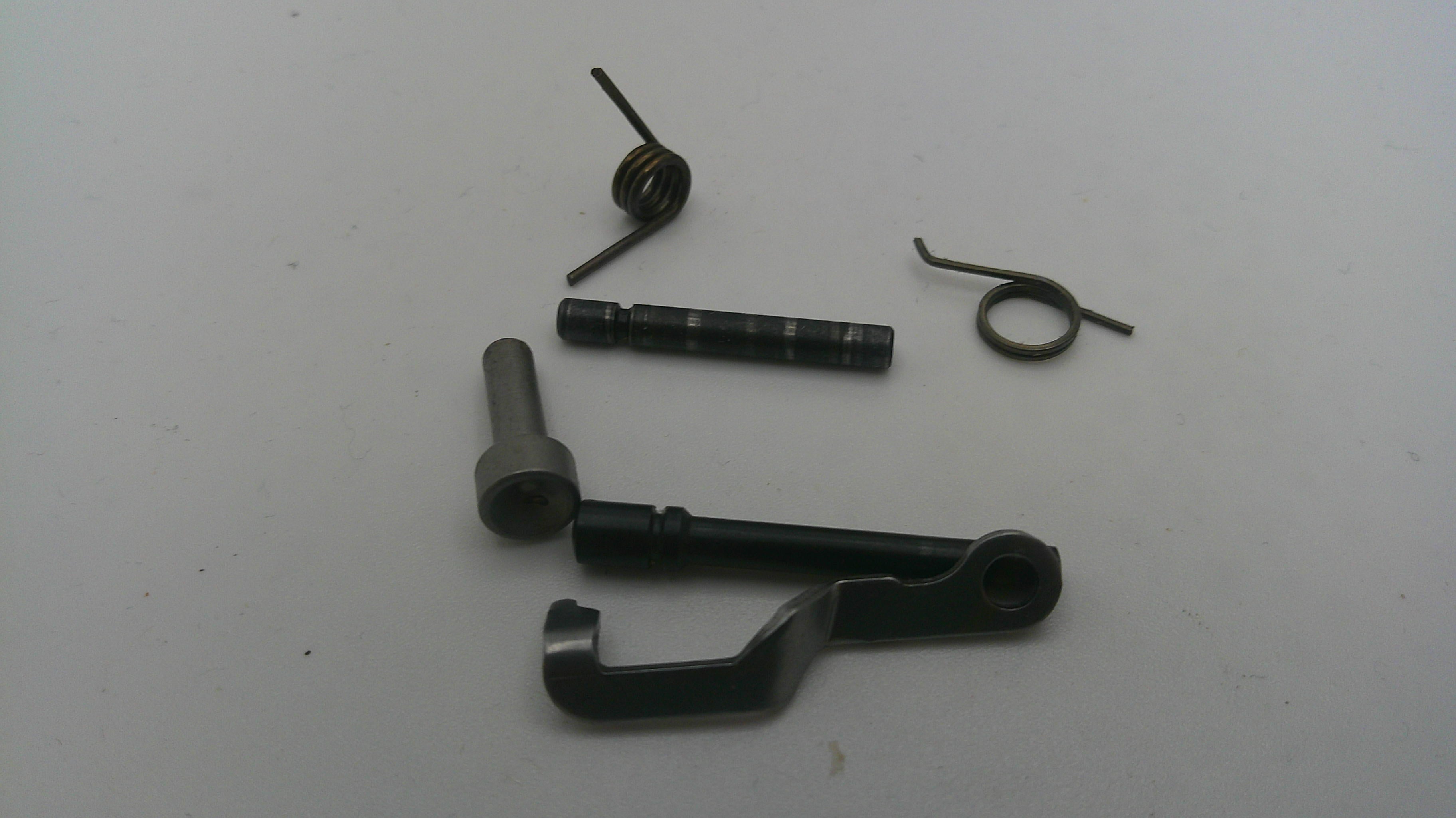 Mechanical parts including a black metal rod, spring, and other components on a white background