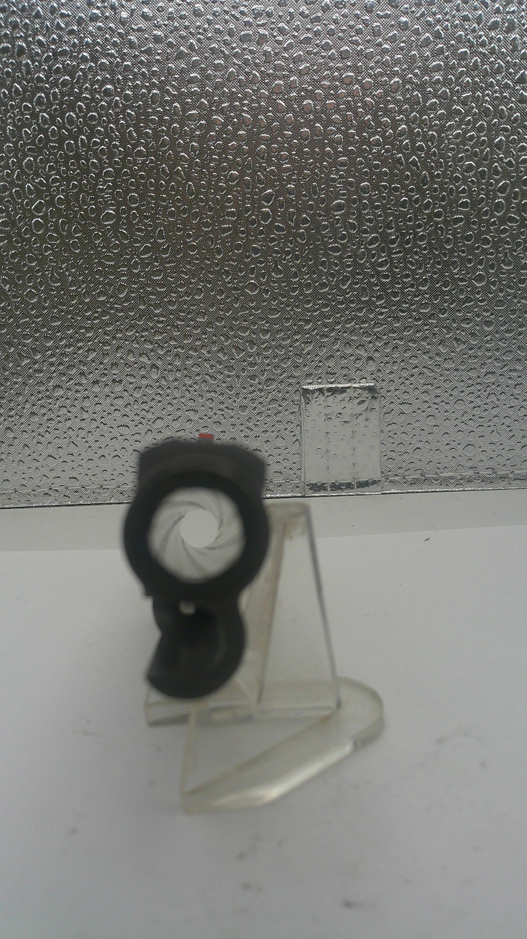 Small black object on a white surface with a textured gray background