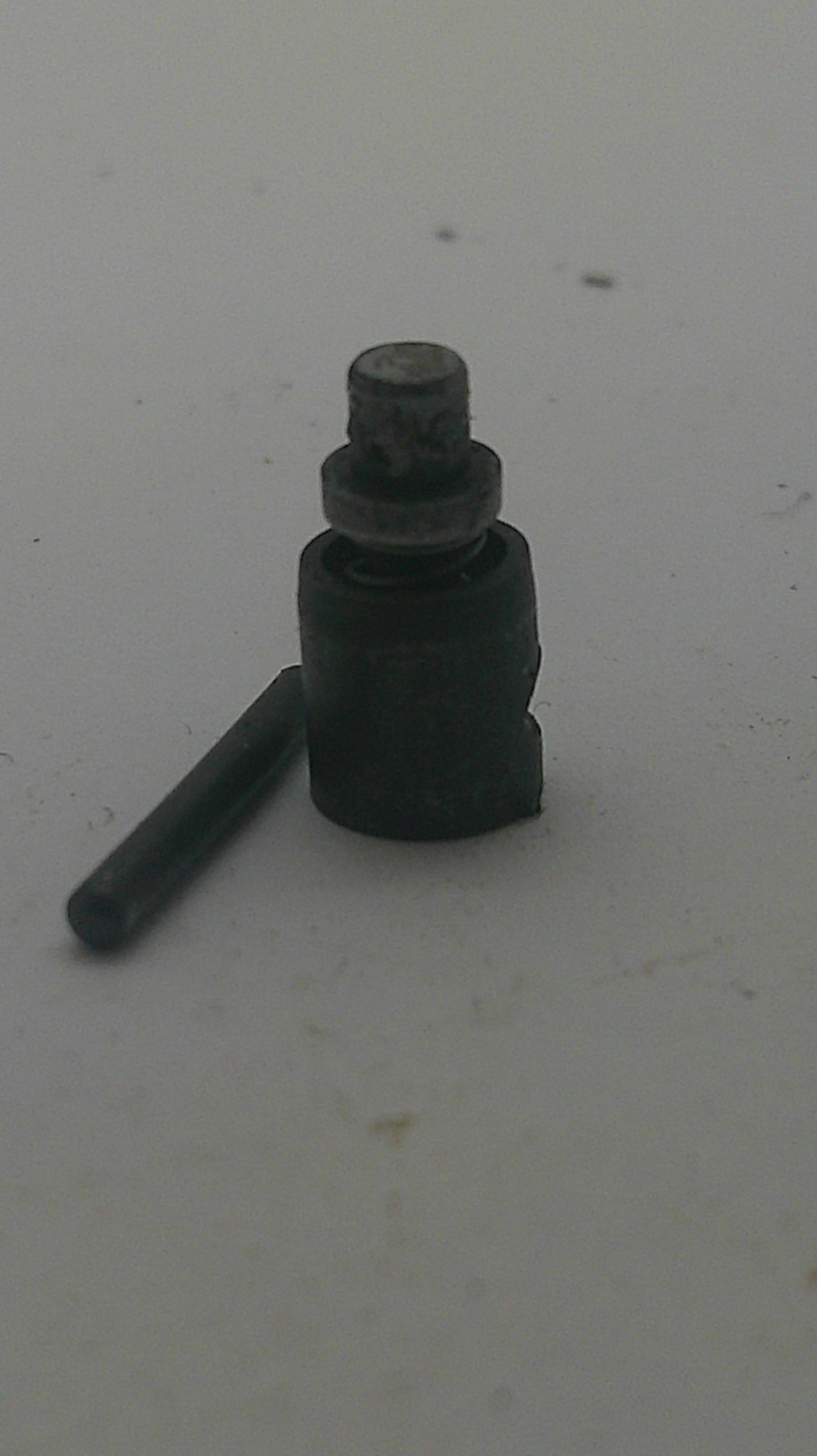 A small black plastic and metal plastic bag hook or hook-and-loop fastener with a short metal rod, shown on a plain off-white background.