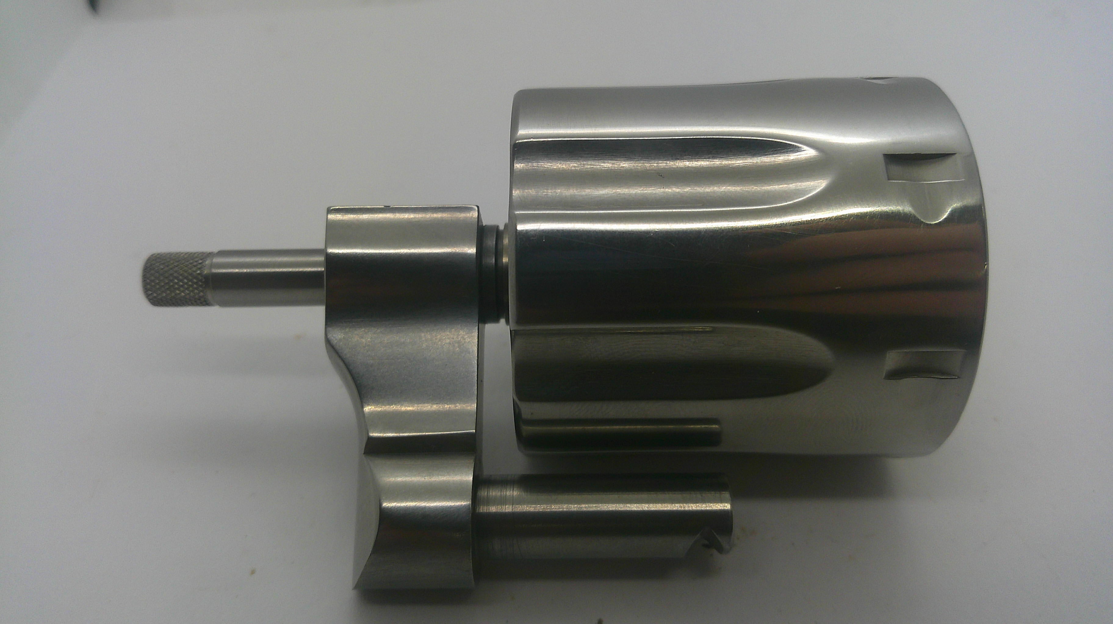 A metallic cylindrical mechanical component with a polished silver finish, featuring a threaded shaft and a small attached rod, photographed on a plain light background.