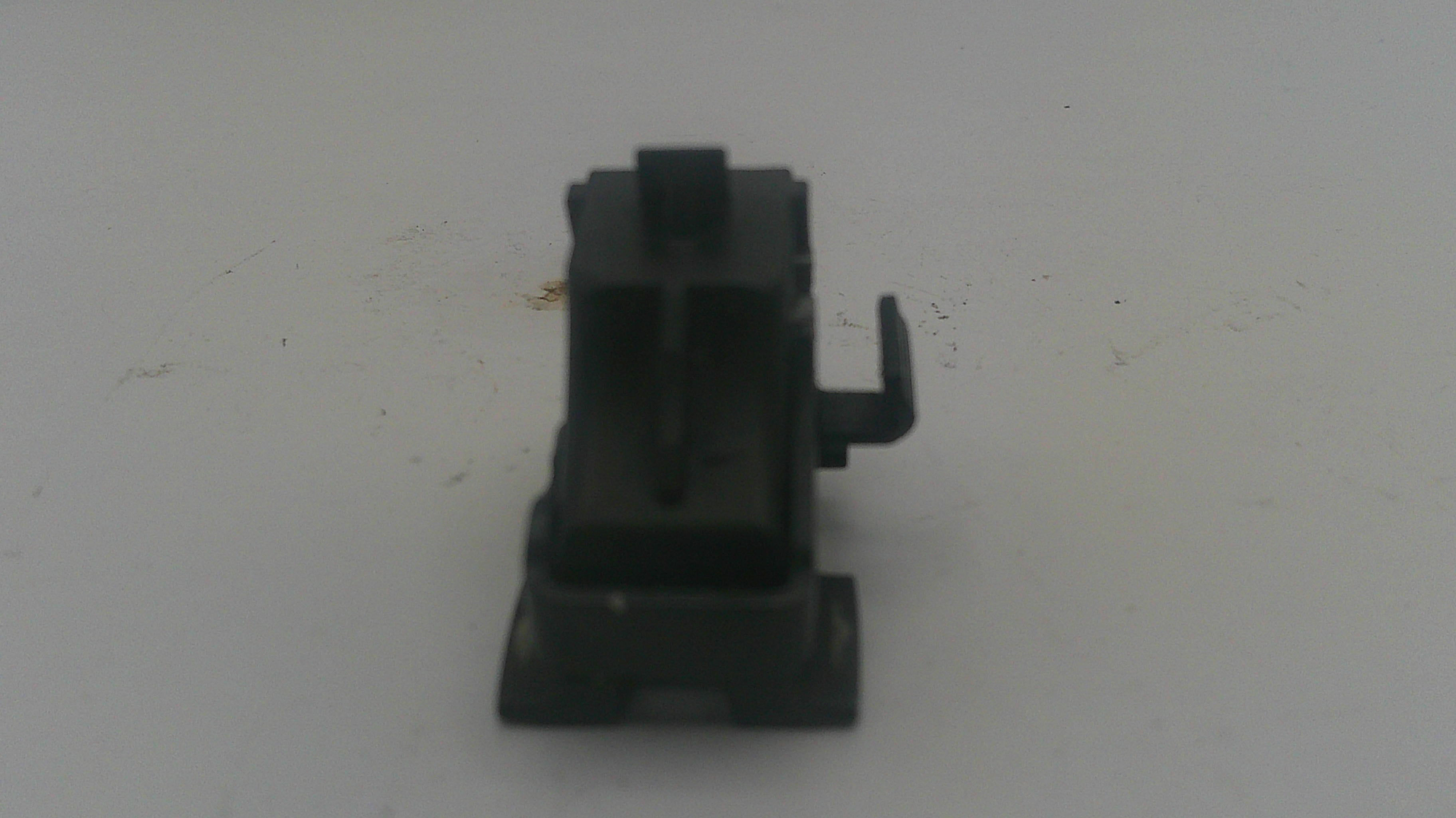 A small black plastic mechanical component or switch with a vertical body and a small side tab, photographed on a plain light background.