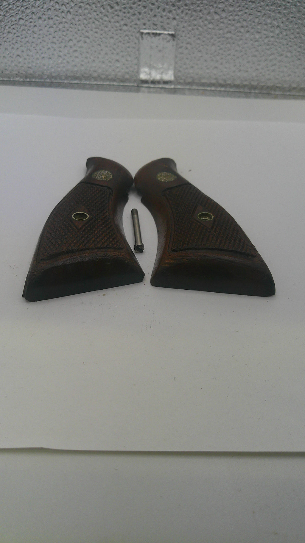Two brown leather gun holsters on a white surface with a textured gray corner.