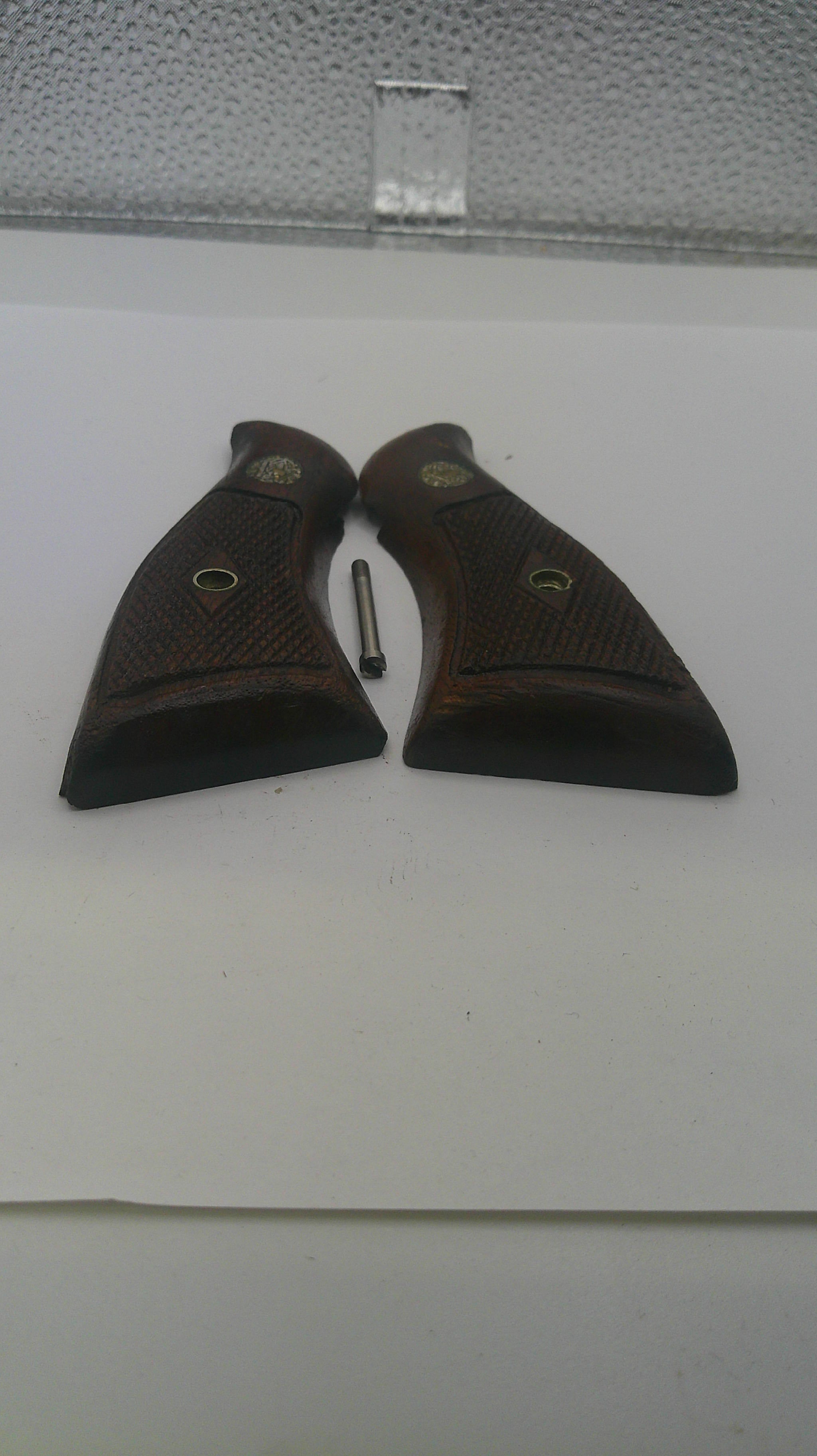 Two brown leather gun holsters on a white surface with a textured gray corner.