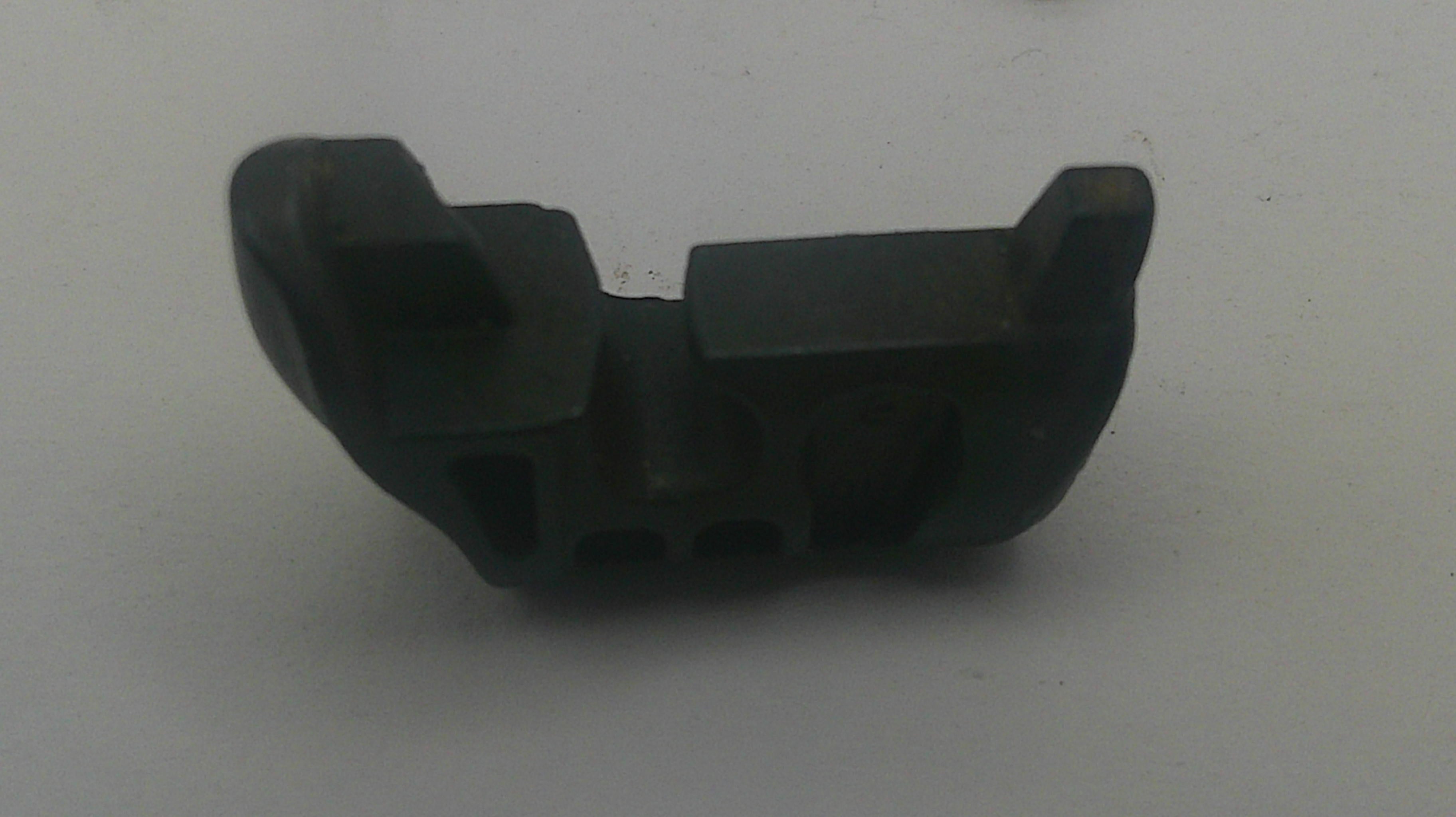 A small black plastic or rubber mechanical component with molded slots and raised tabs, photographed on a plain light gray background.