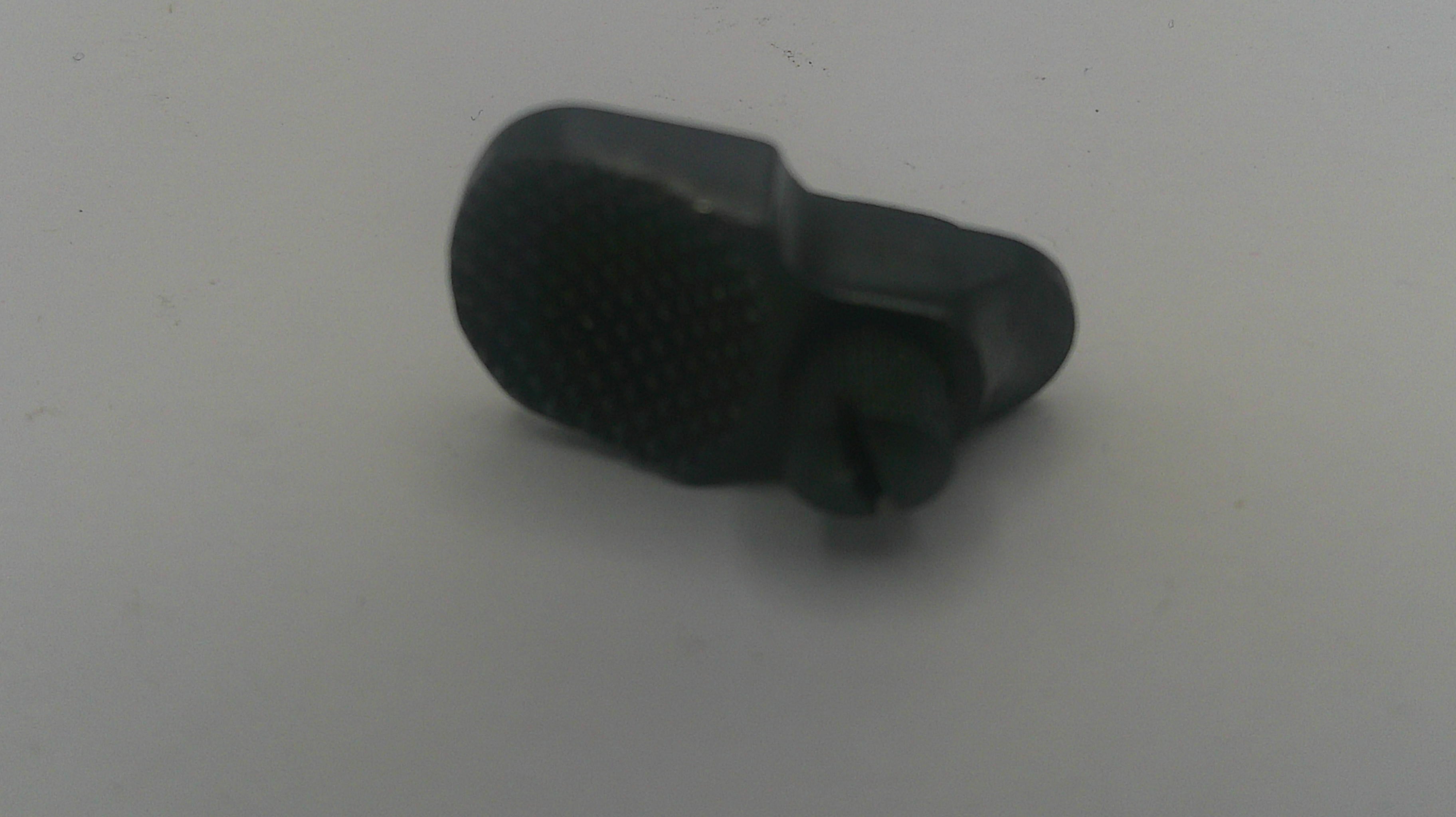 A small black plastic replacement part with a textured oval top and a cylindrical protruding end, shown on a plain light gray background.