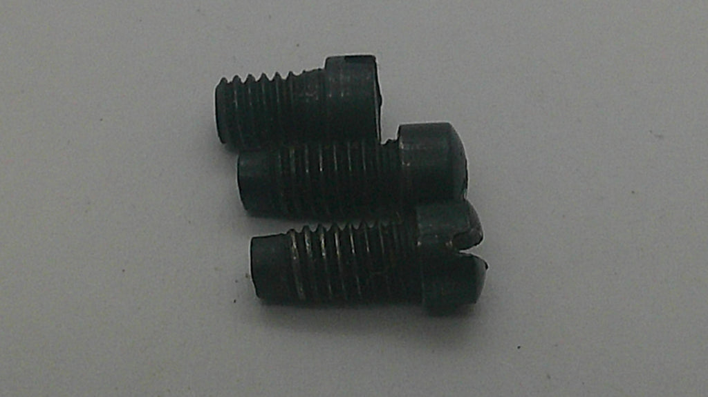 Three small black threaded screws with slotted countersunk heads, arranged vertically on a plain light gray surface.