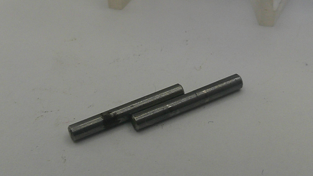 Two metallic pins on a light gray surface