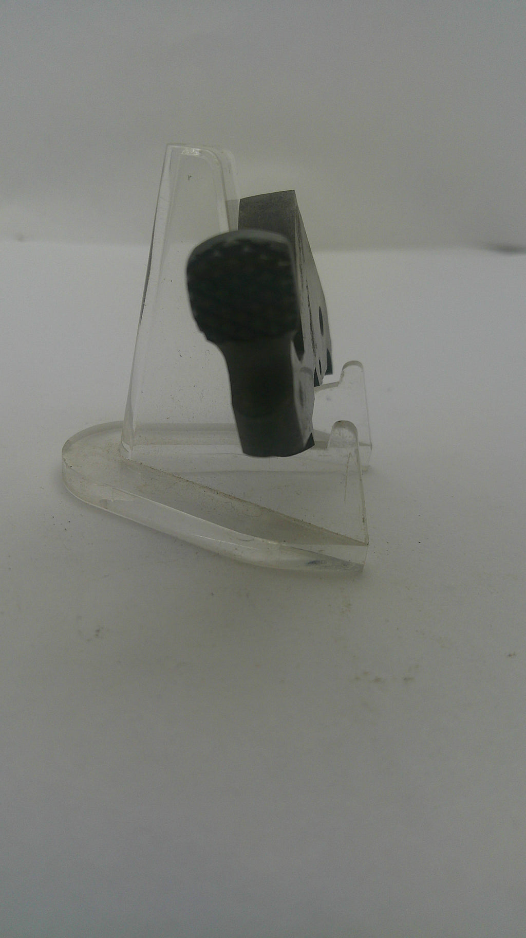 A small black handheld microphone clipped to a clear plastic display stand against a plain white background.