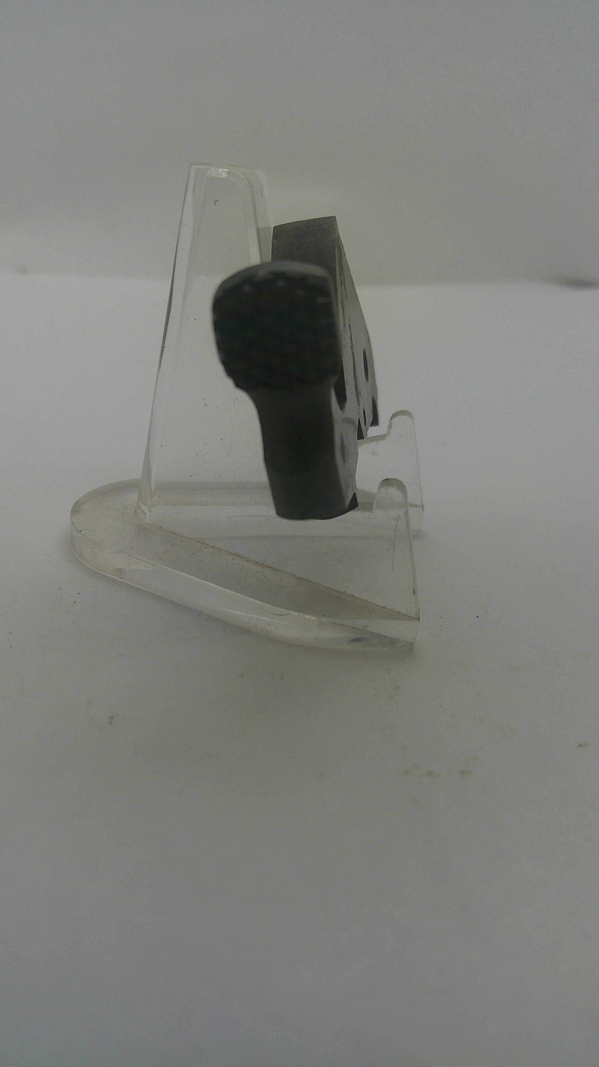 A small black handheld microphone clipped to a clear plastic display stand against a plain white background.