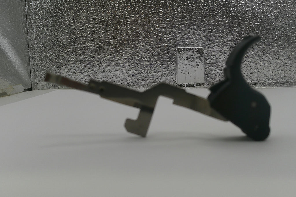 Metallic tool with a black handle on a textured surface