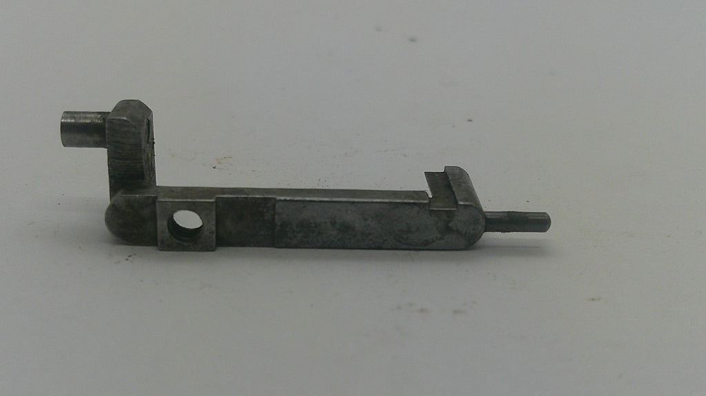 A small dark metal mechanical component or hardware piece with a rectangular body, circular hole, angled joint, and protruding pin, photographed on a plain light background.
