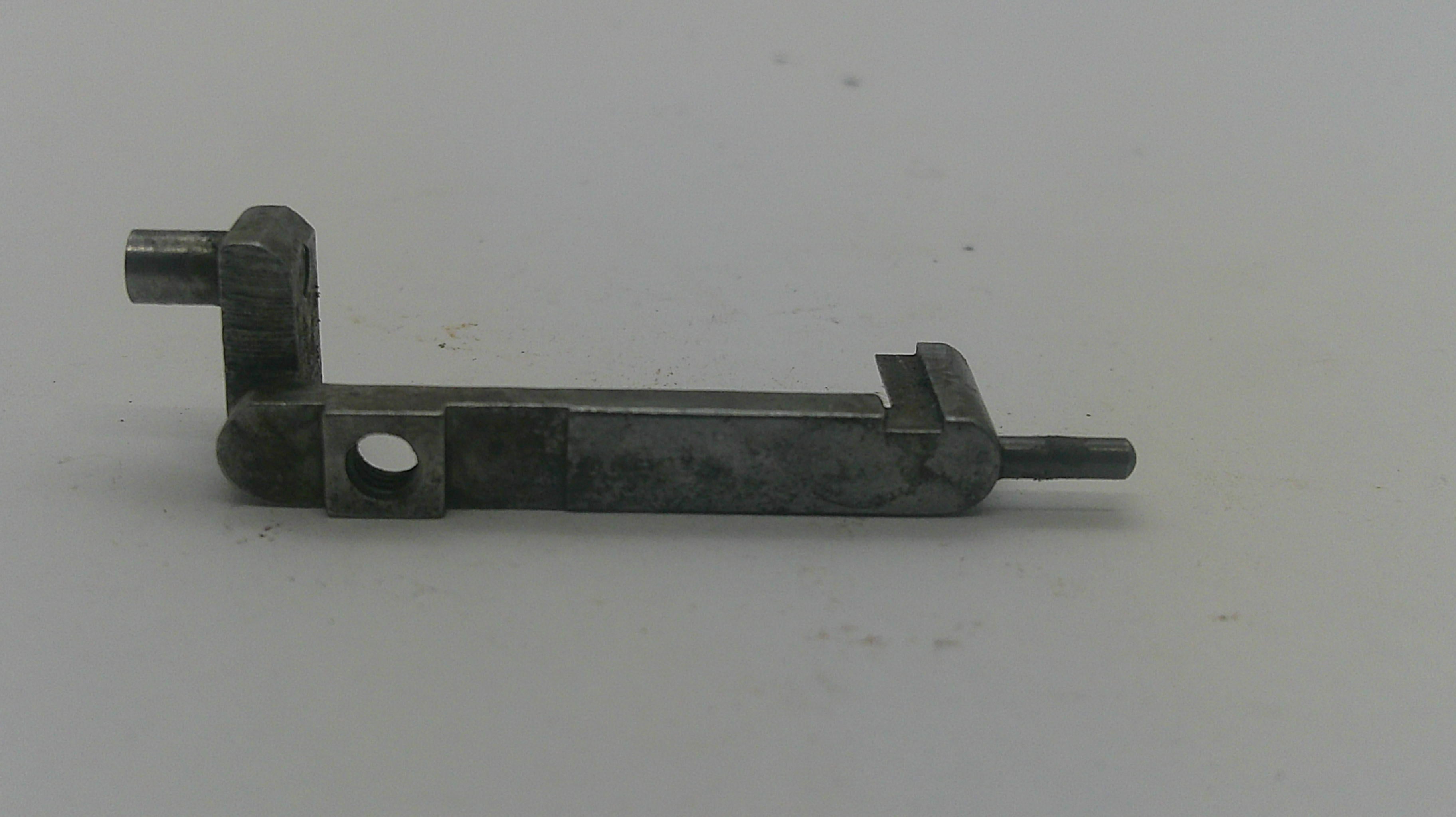 A small dark metal mechanical component or hardware piece with a rectangular body, circular hole, angled joint, and protruding pin, photographed on a plain light background.