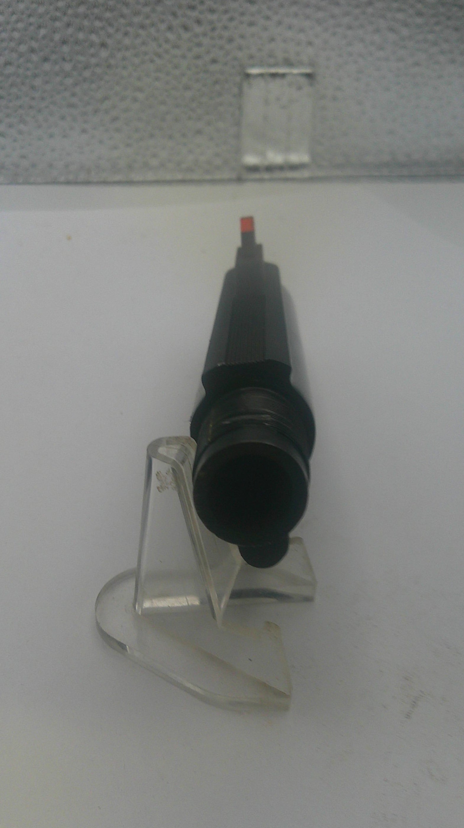 Clear plastic stand with a black object on a white background