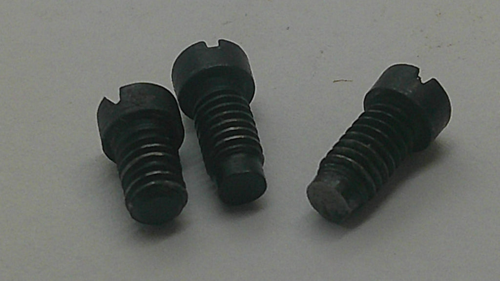 Three small black threaded metal screws or bolts with slotted heads, arranged on a plain light gray surface.
