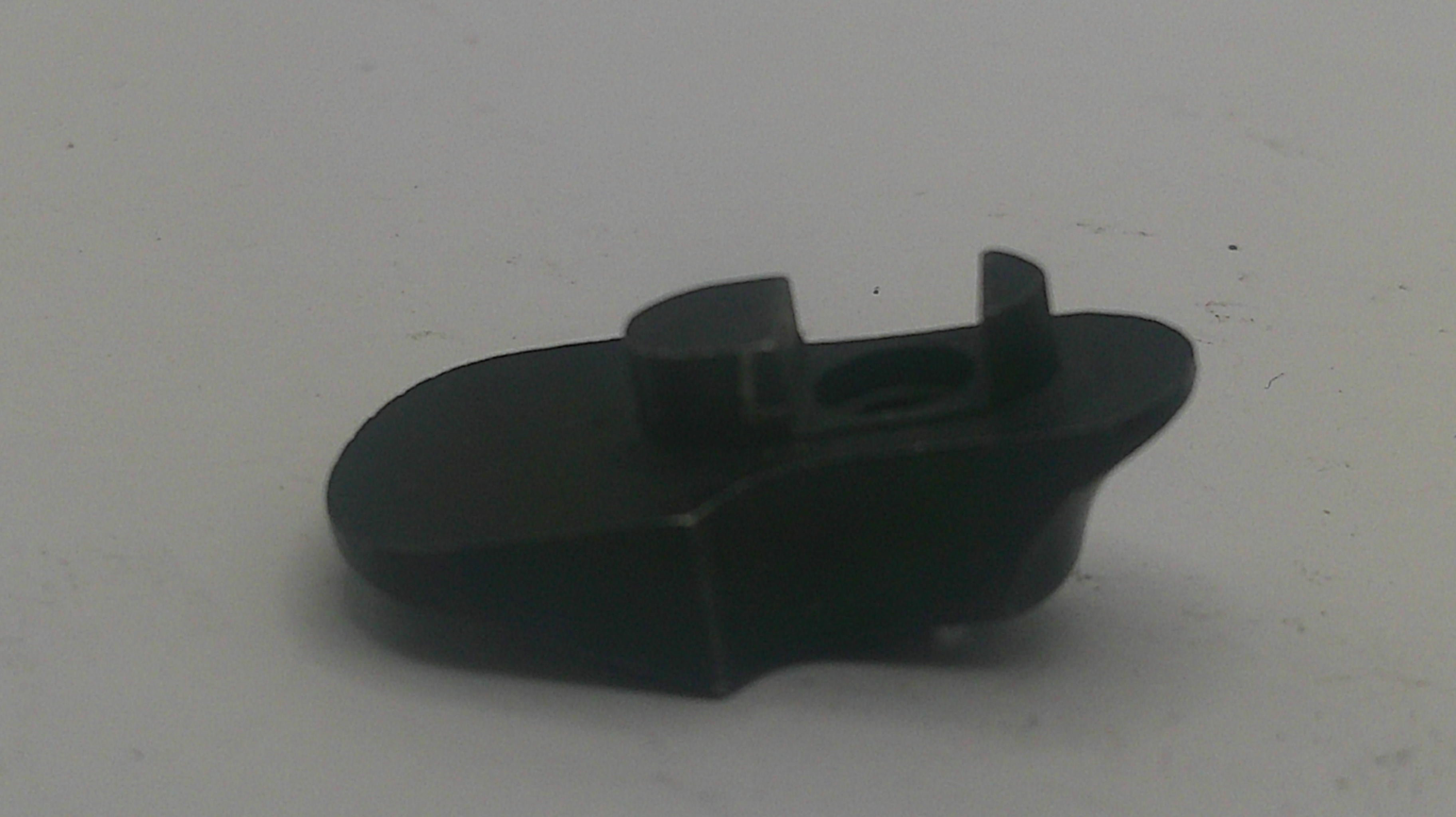 A small black plastic component with a curved, boot-like shape and a central slot, photographed on a plain light gray surface.
