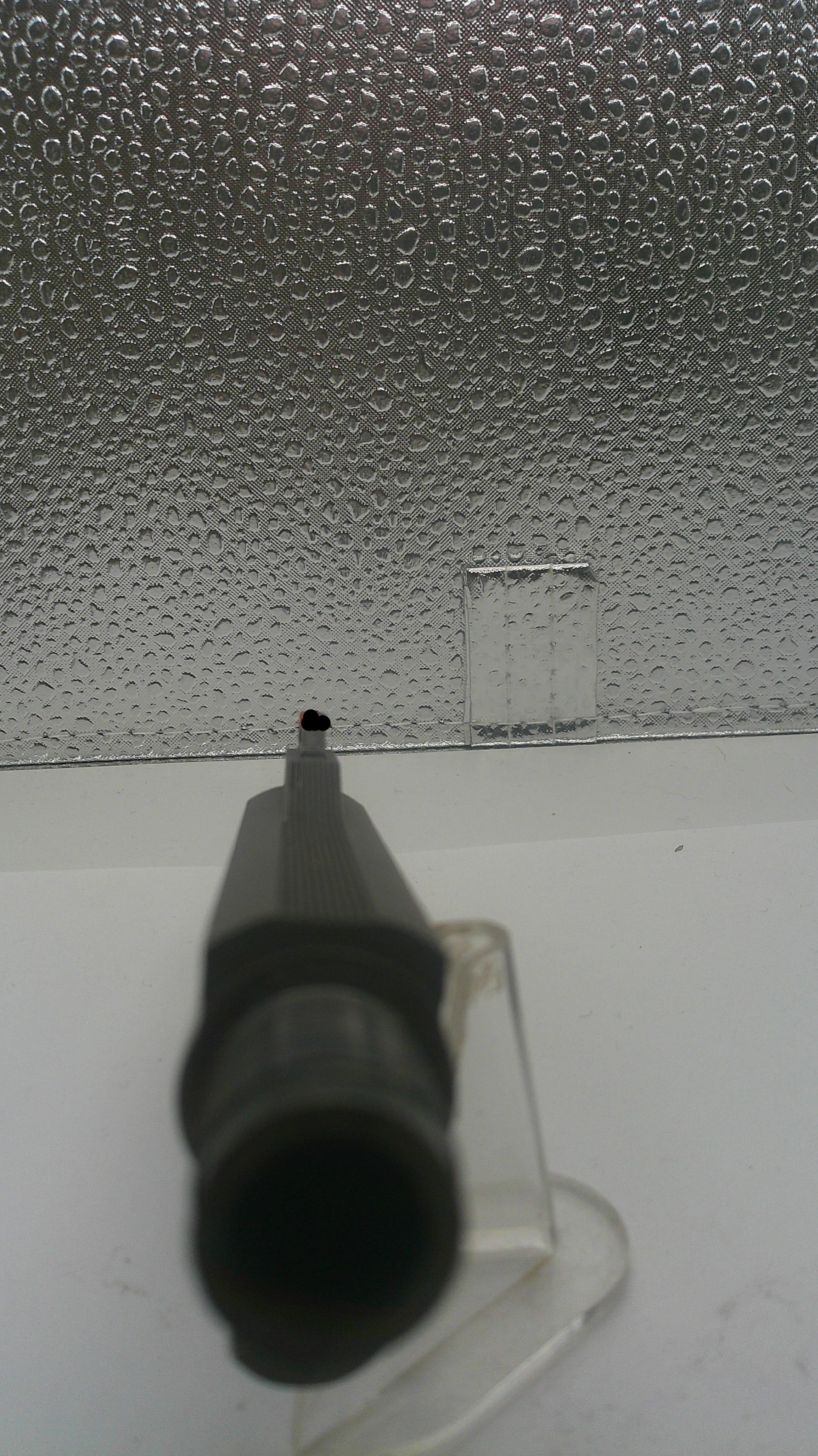 Close-up of a textured surface with a small red object on a white background