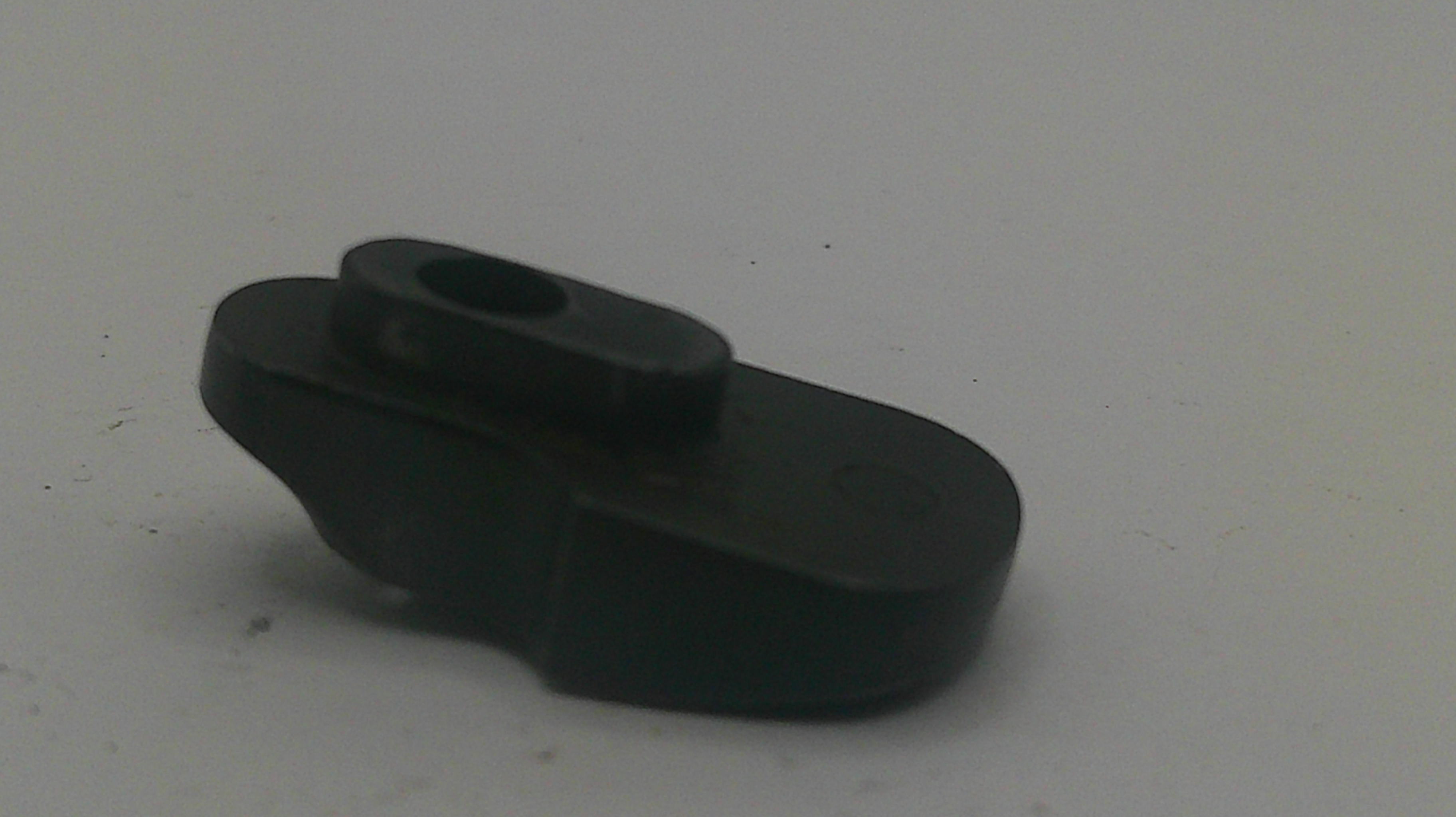 A small black plastic or rubber component with a circular hole, photographed on a plain light gray background.