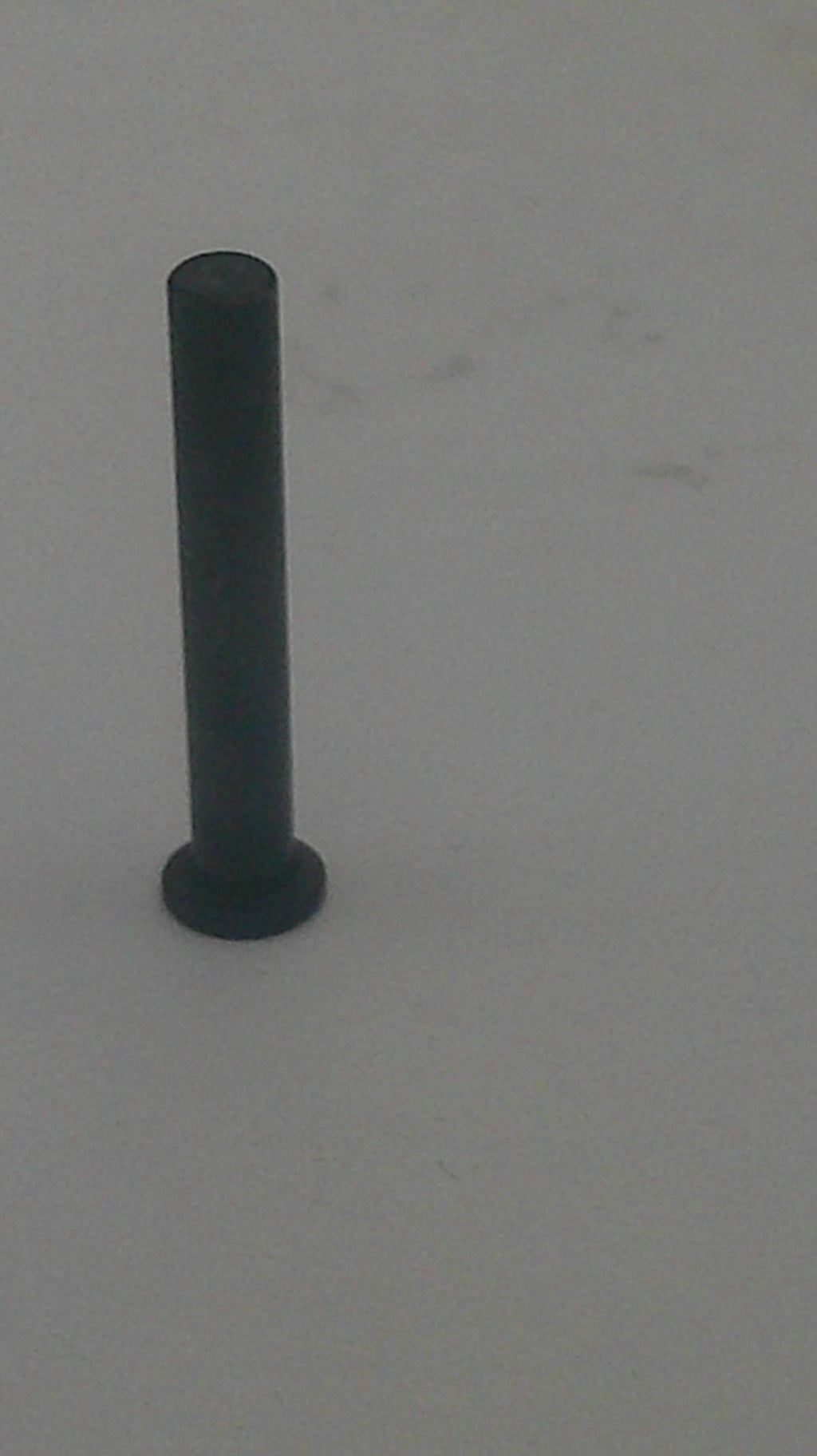 A single black metal wall hook or peg mounted on a plain light gray wall.