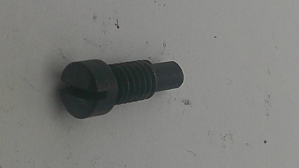 A small black metal threaded fastener or screw component with a slotted head, lying on a light gray surface.