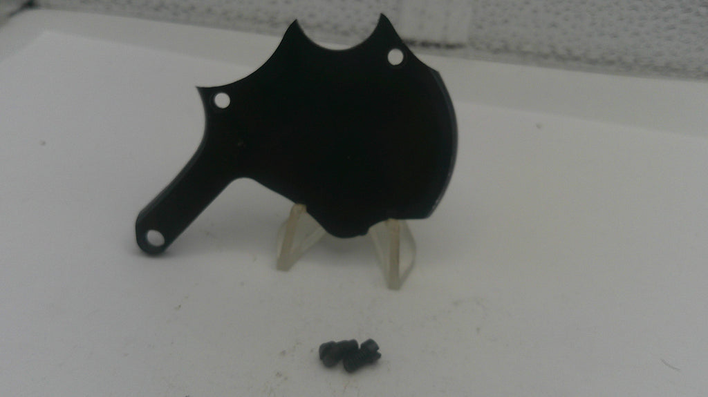 Black metal object on a stand with small black components on a white surface