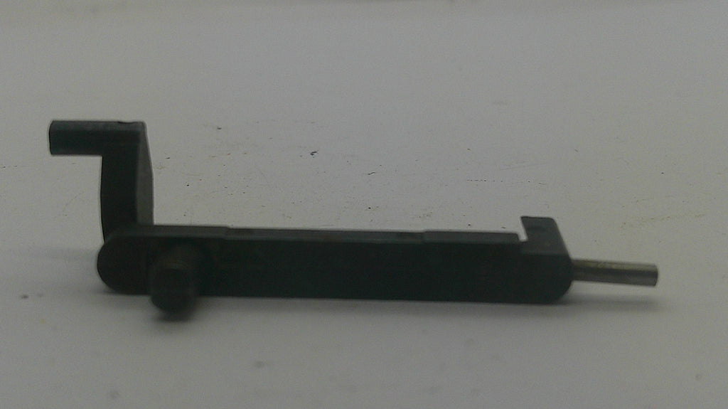 A small black metal hardware component with a flat rectangular body, a bent L-shaped arm on the left, a round knob-like detail, and a thin silver rod extending to the right, photographed on a plain light background.