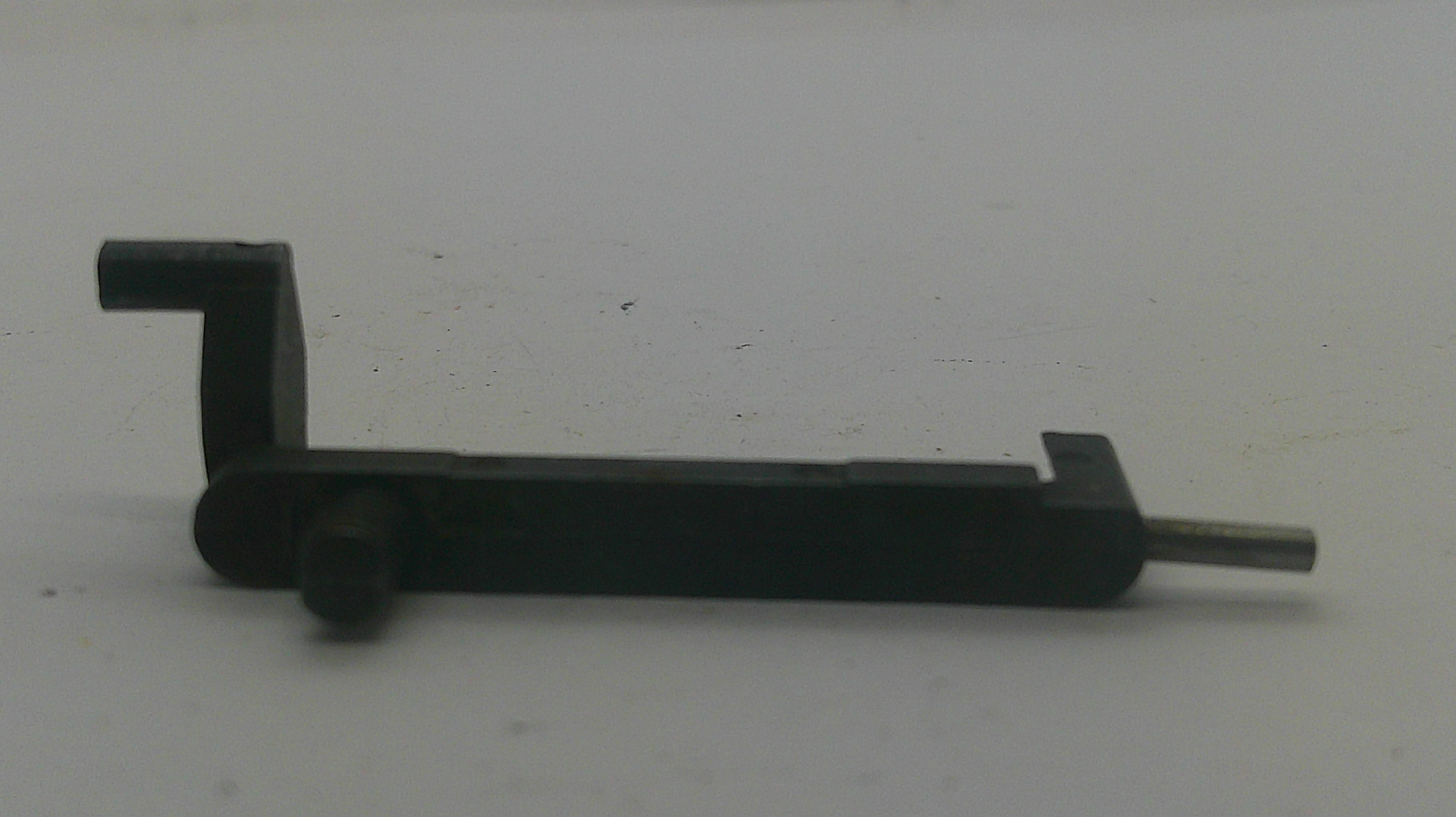 A small black metal hardware component with a flat rectangular body, a bent L-shaped arm on the left, a round knob-like detail, and a thin silver rod extending to the right, photographed on a plain light background.