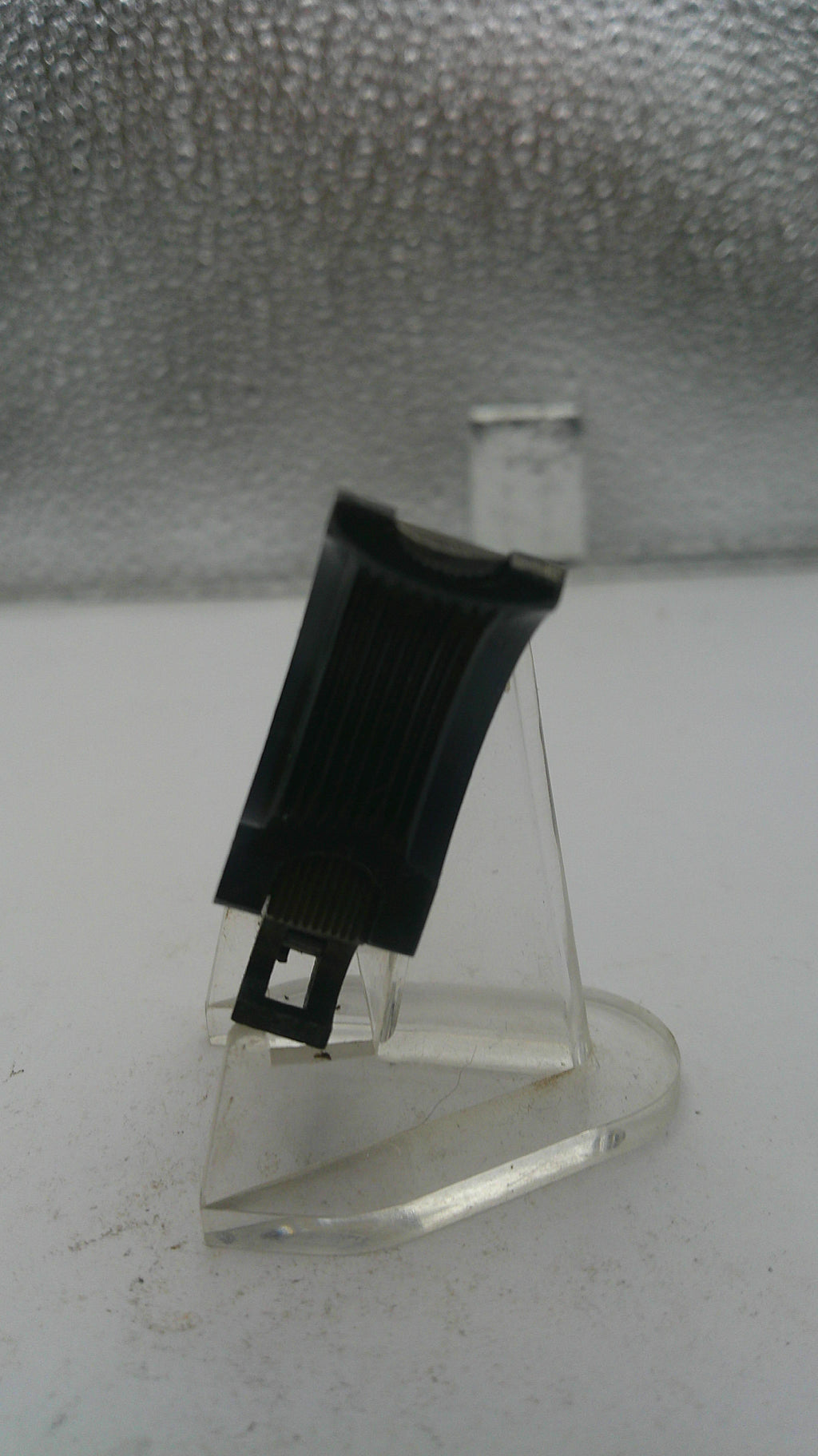 Metal bracket with a black clip on a textured wall
