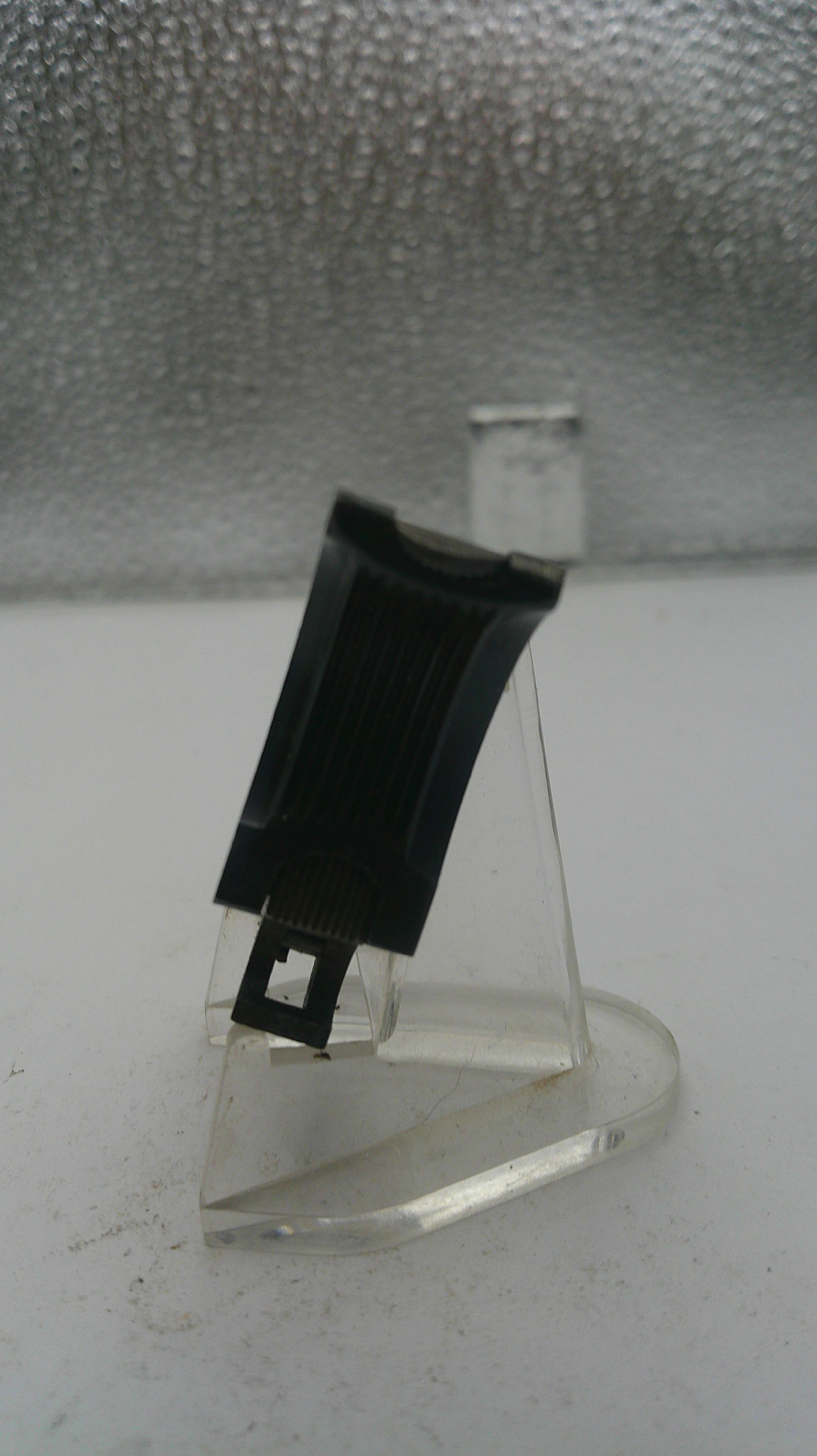 Metal bracket with a black clip on a textured wall