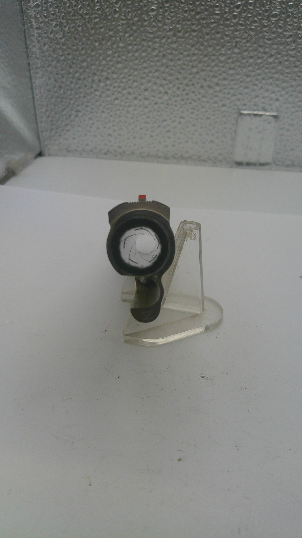 Mechanical component on a white stand with a textured wall background