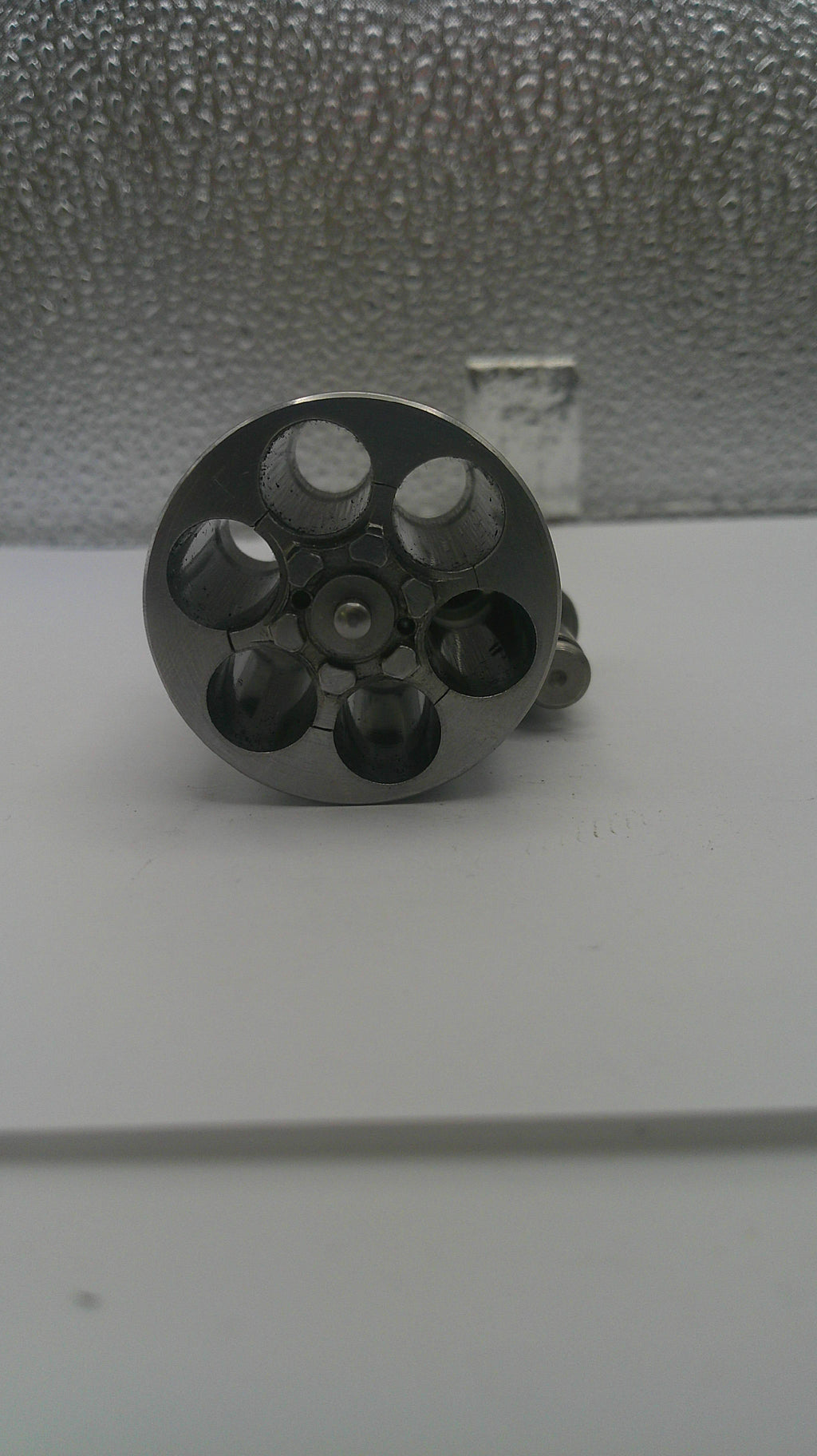 Close-up of a metallic object with multiple holes on a textured surface