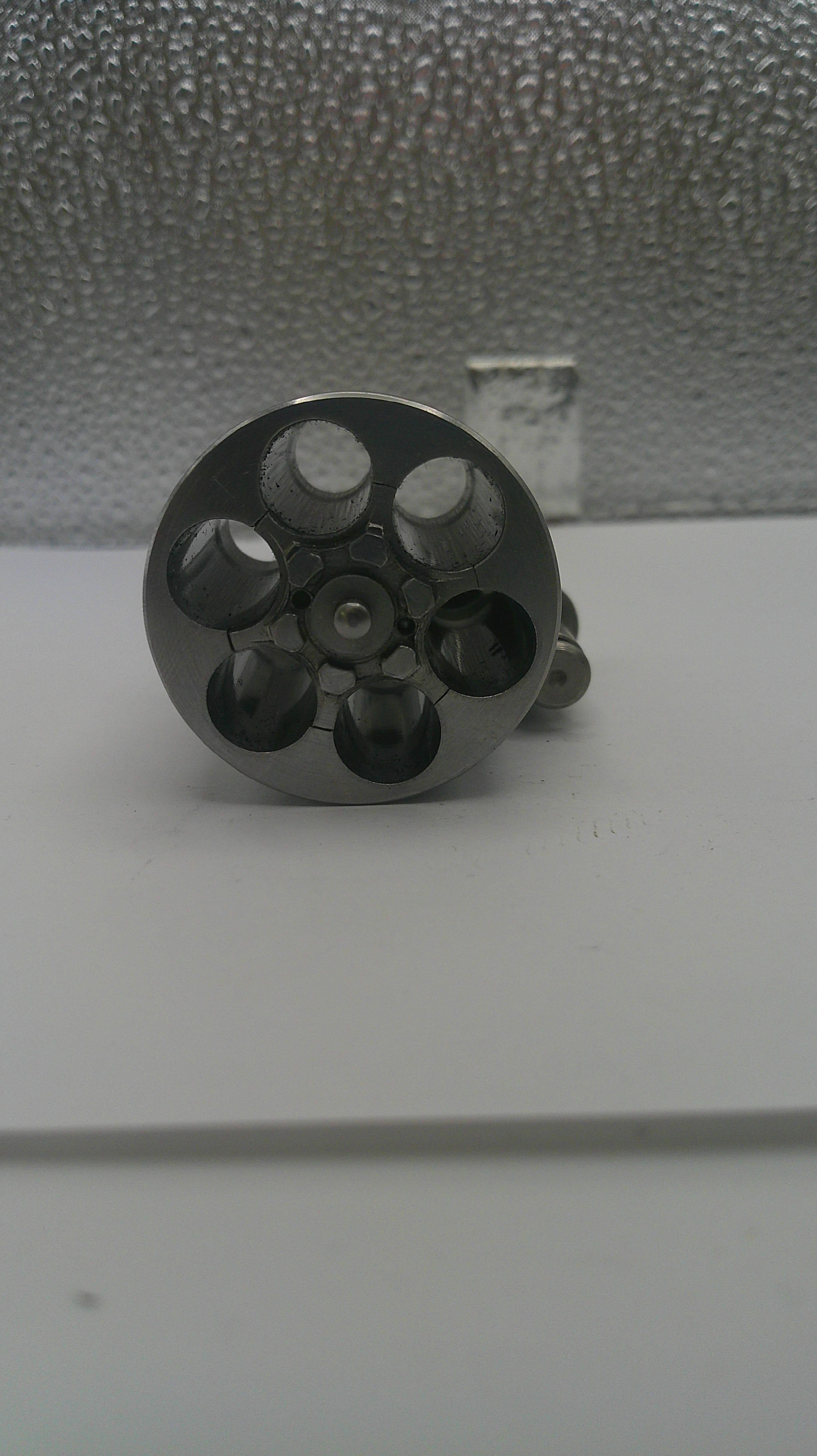 Close-up of a metallic object with multiple holes on a textured surface