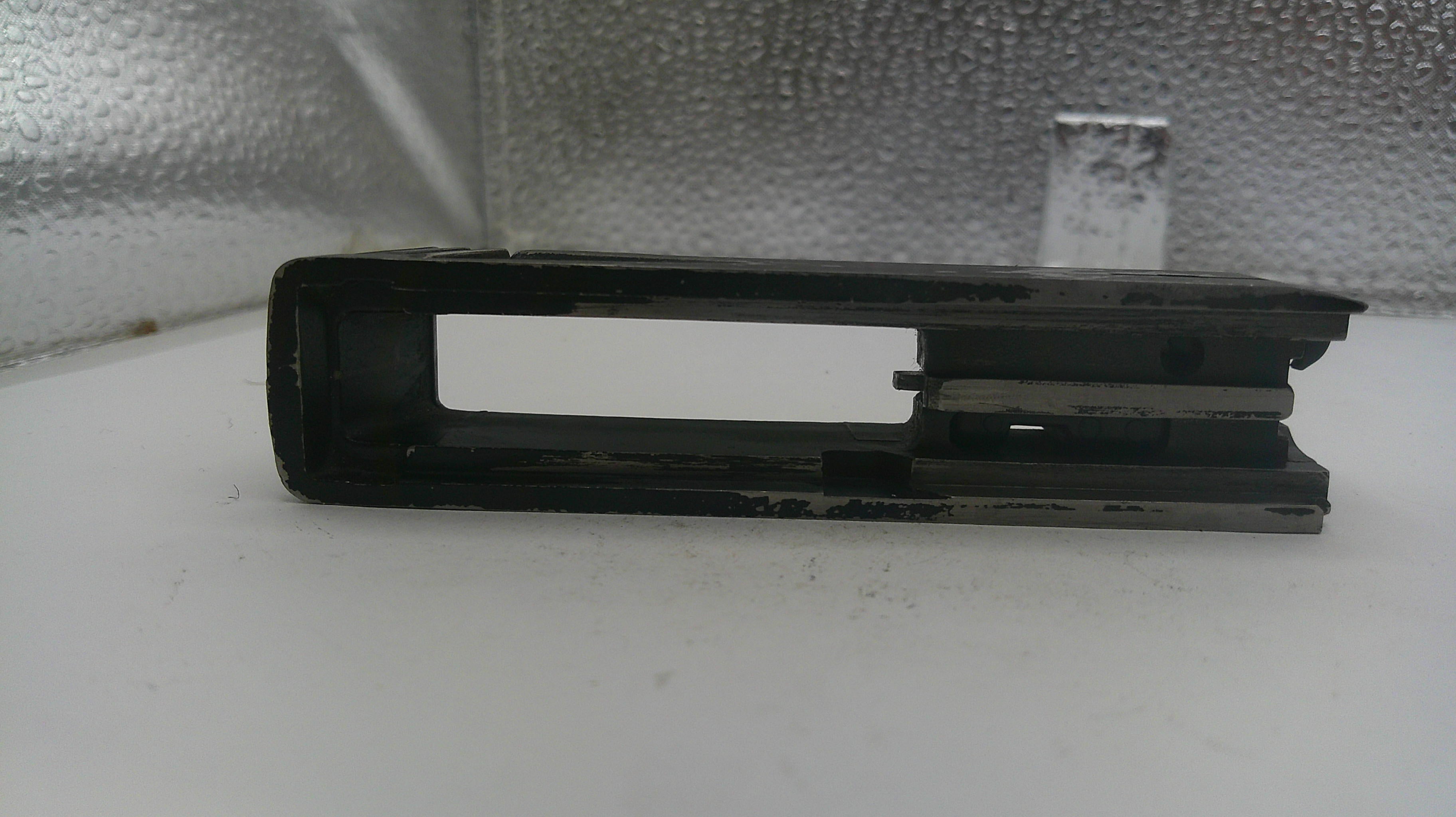 Black metal bracket on a white surface with a reflective silver background