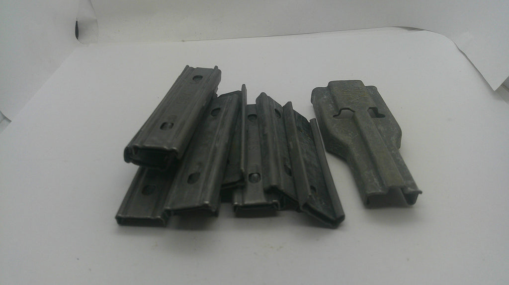 A set of dark gray plastic or metal magazine clips or inserts arranged on a plain white surface.
