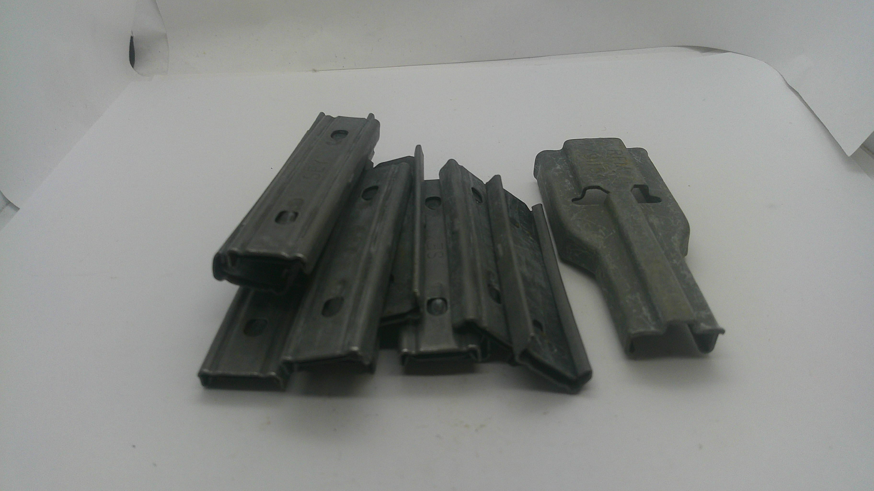 A set of dark gray plastic or metal magazine clips or inserts arranged on a plain white surface.