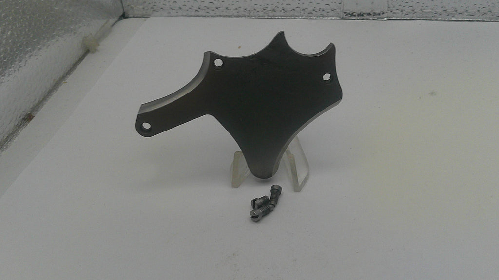 Black motorcycle part on a white surface with a textured wall background