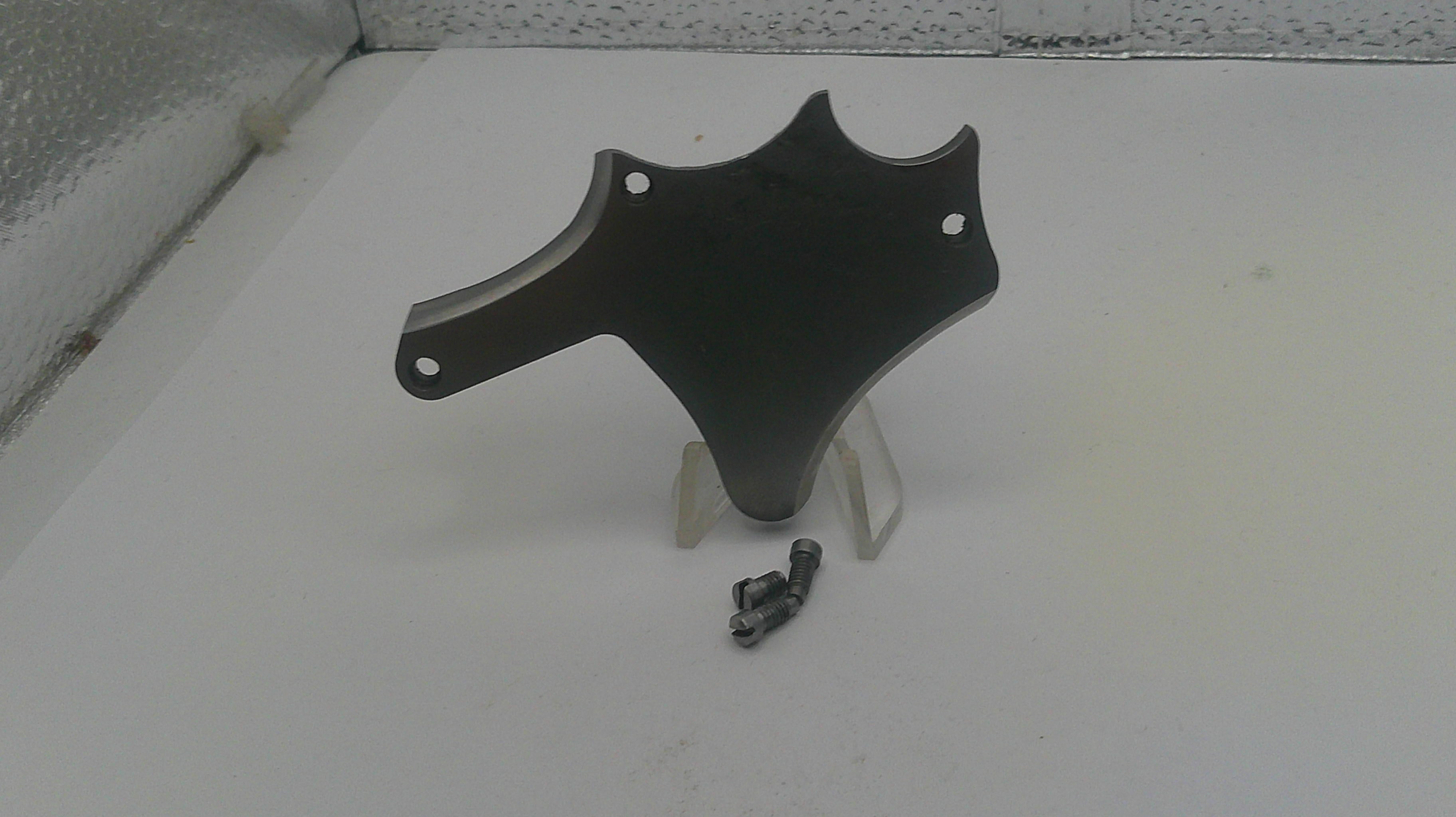 Black motorcycle part on a white surface with a textured wall background