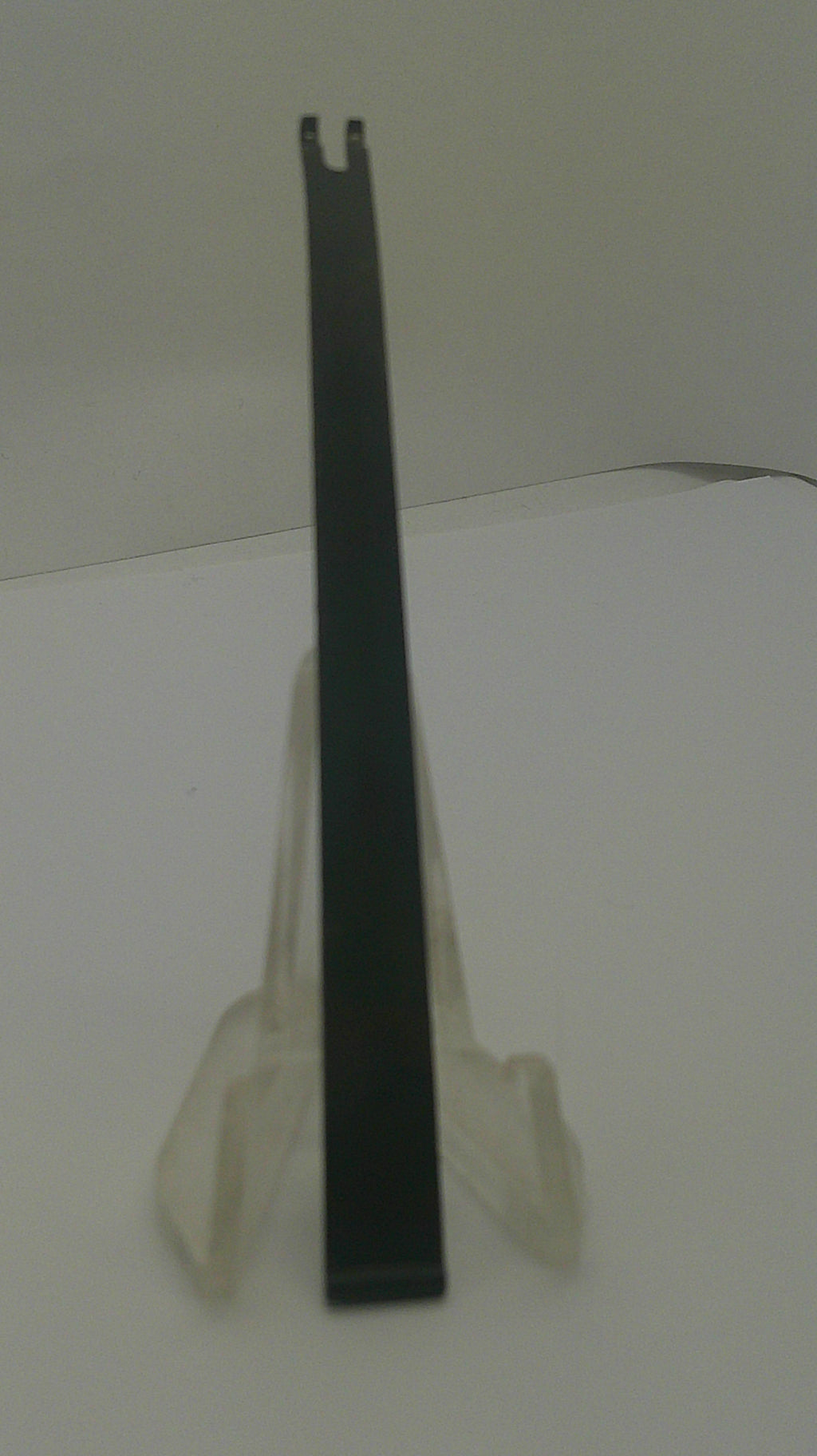 A long, flat black metal tool with a forked end, photographed against a plain off-white background.