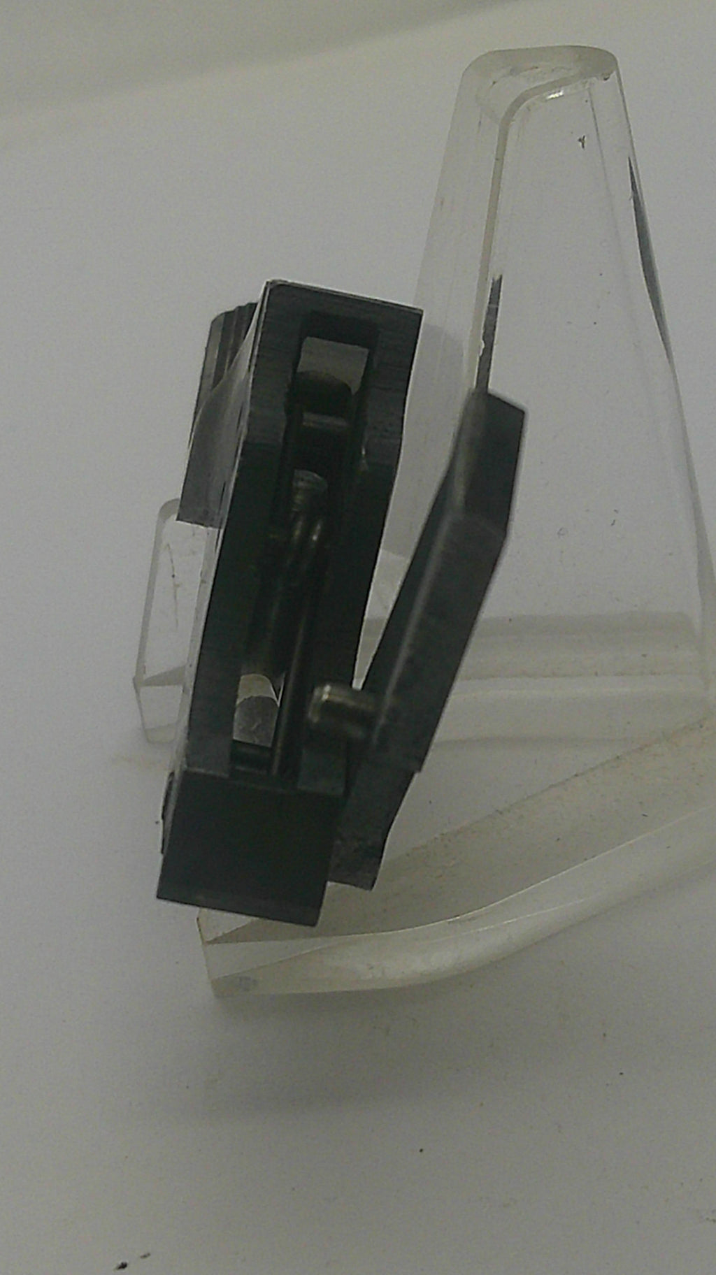 A close-up of a black plastic clip or fastener with a clear plastic backing, shown against a plain white background.