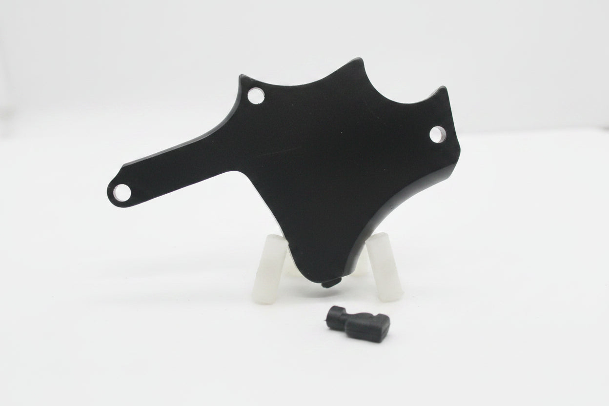 A black metal mounting bracket or cover with pre-drilled holes, displayed on a small clear stand against a plain light gray background.