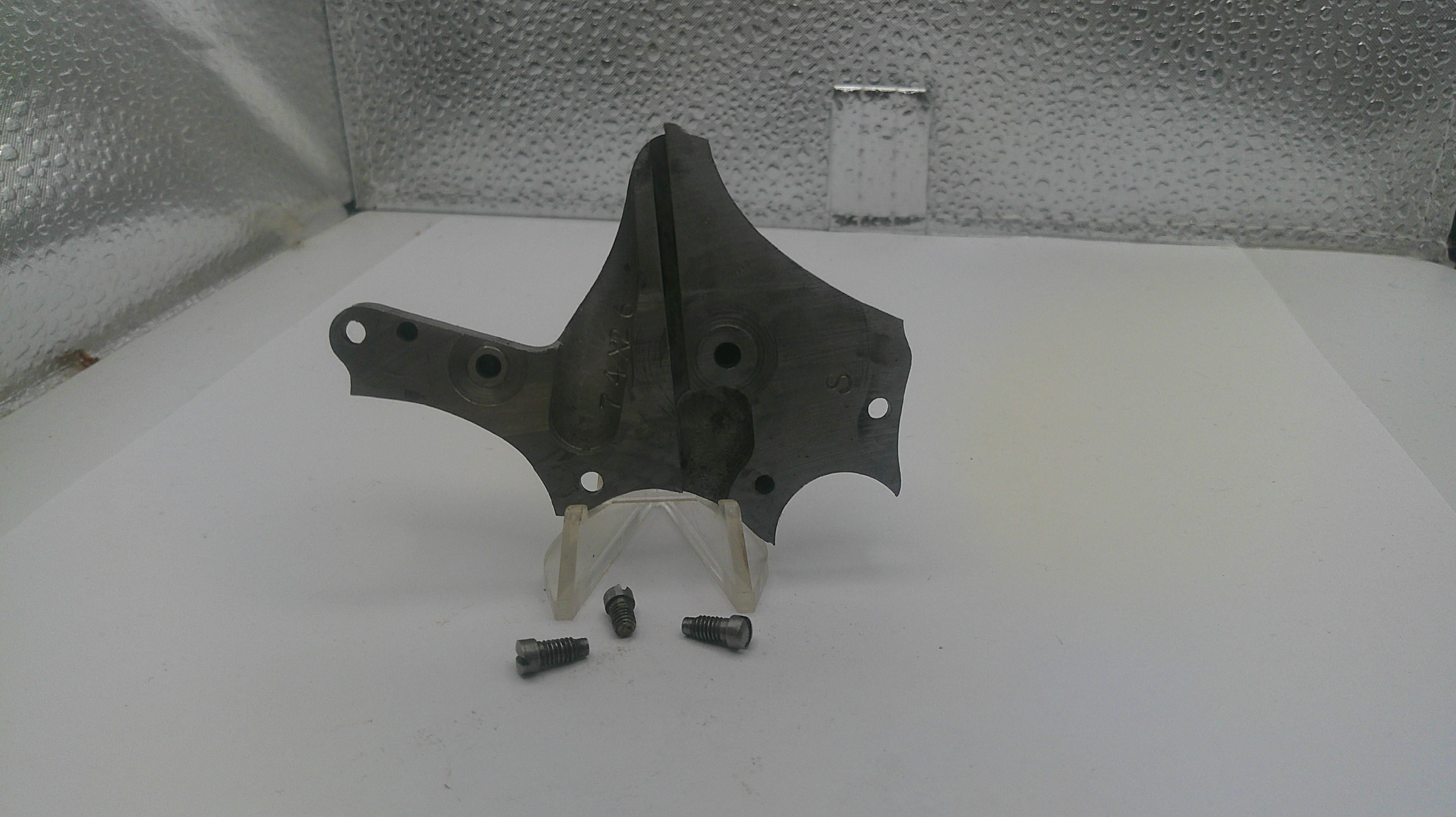 Metal bracket with screws on a white surface with a textured wall background