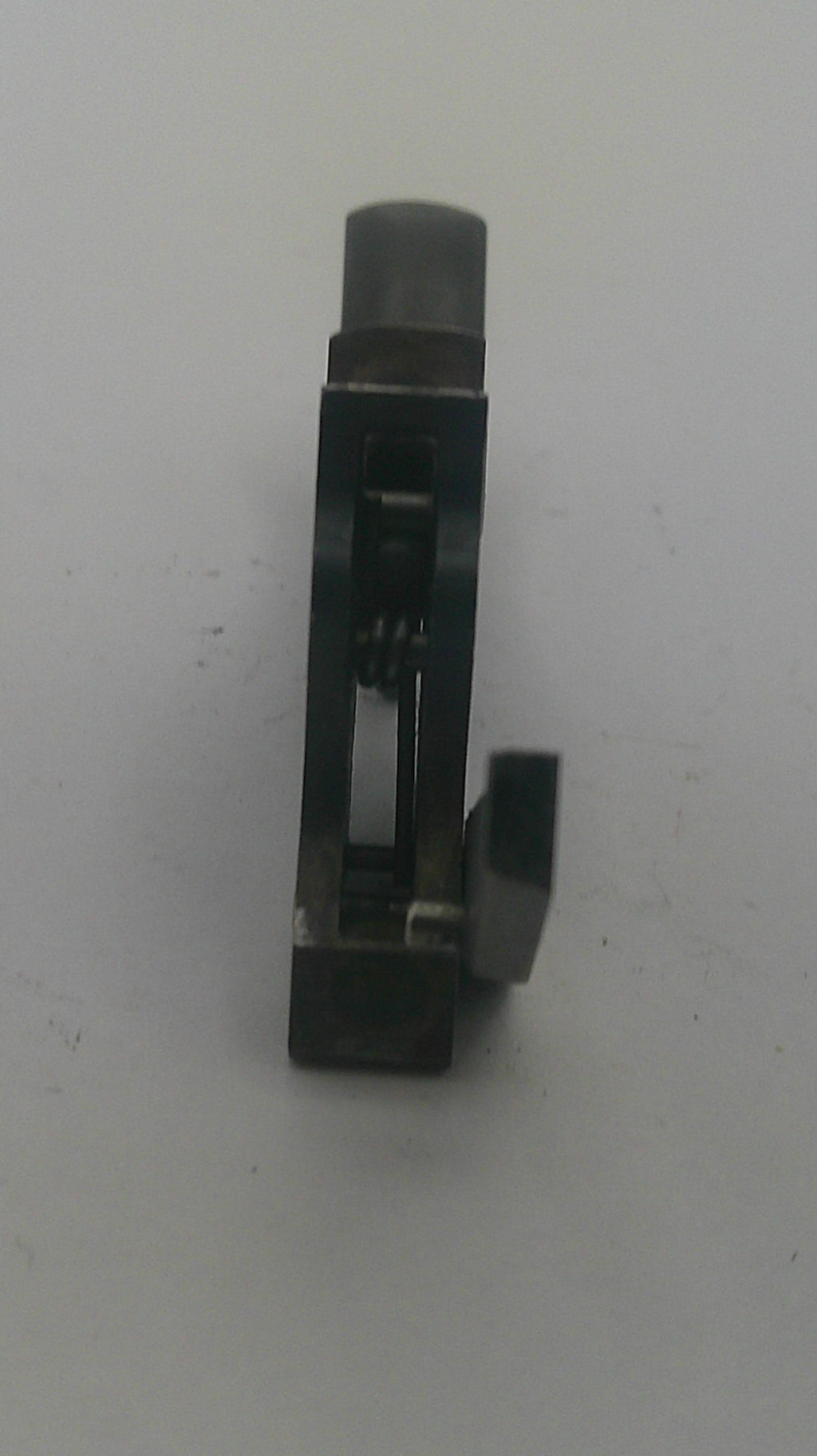 A small black metal mechanical component or tool part with a cylindrical end, photographed on a plain light background.