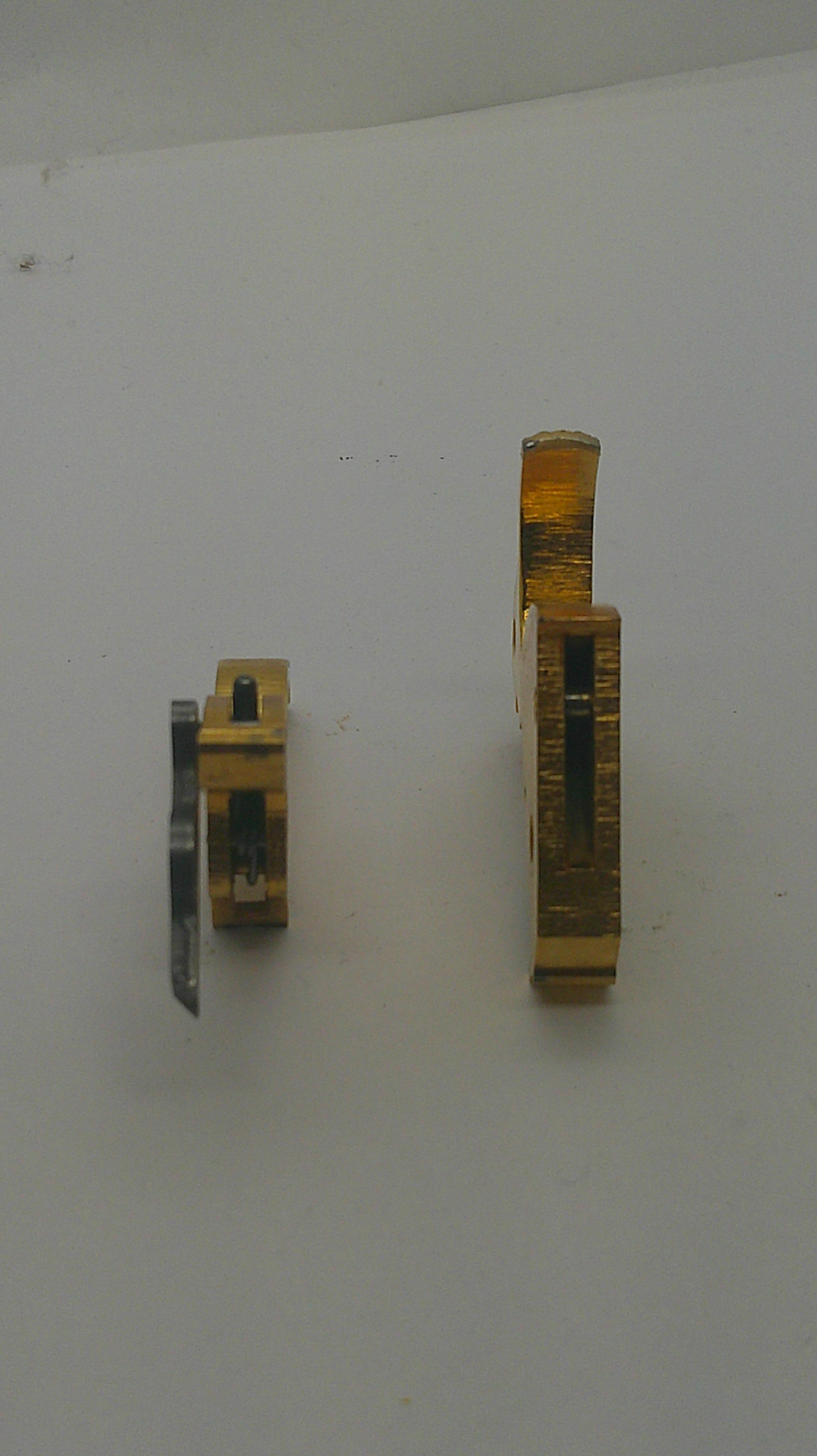 Two brass door hardware components, likely locksets or latch hardware, displayed on a plain off-white background.