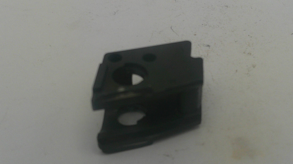 A small black plastic mechanical component or clip with circular cutouts, photographed on a plain off-white surface.