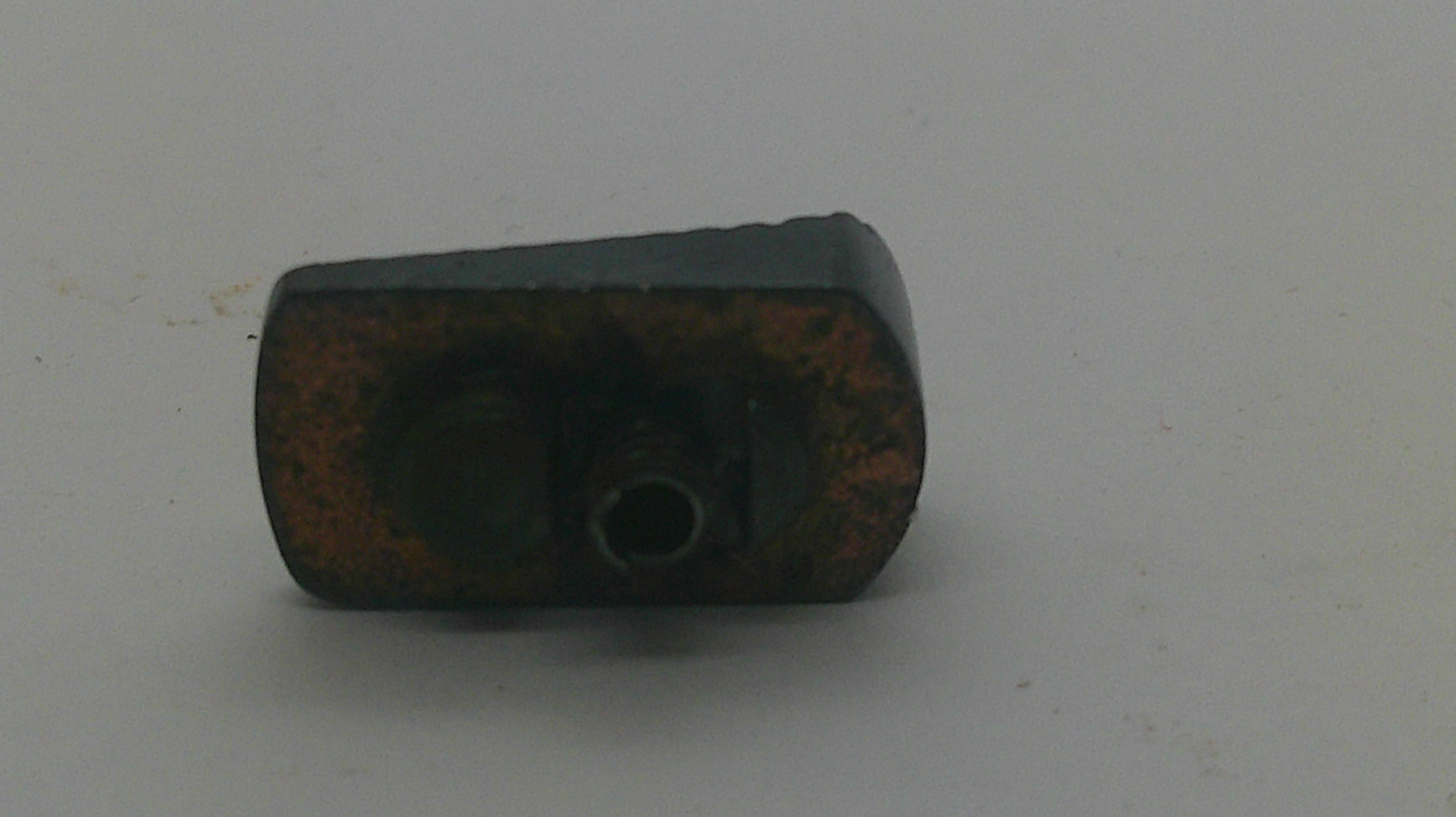 A small dark metal mechanical component with a rusted brown surface, photographed on a plain light gray background.