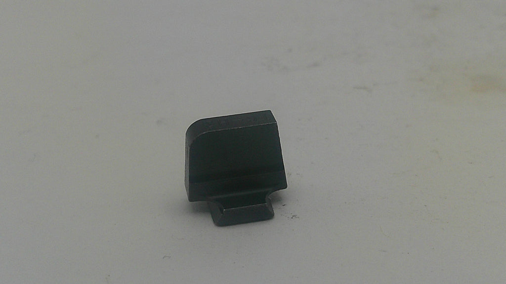 A small black plastic component, possibly a lens protector or cap, standing upright on a light gray surface.