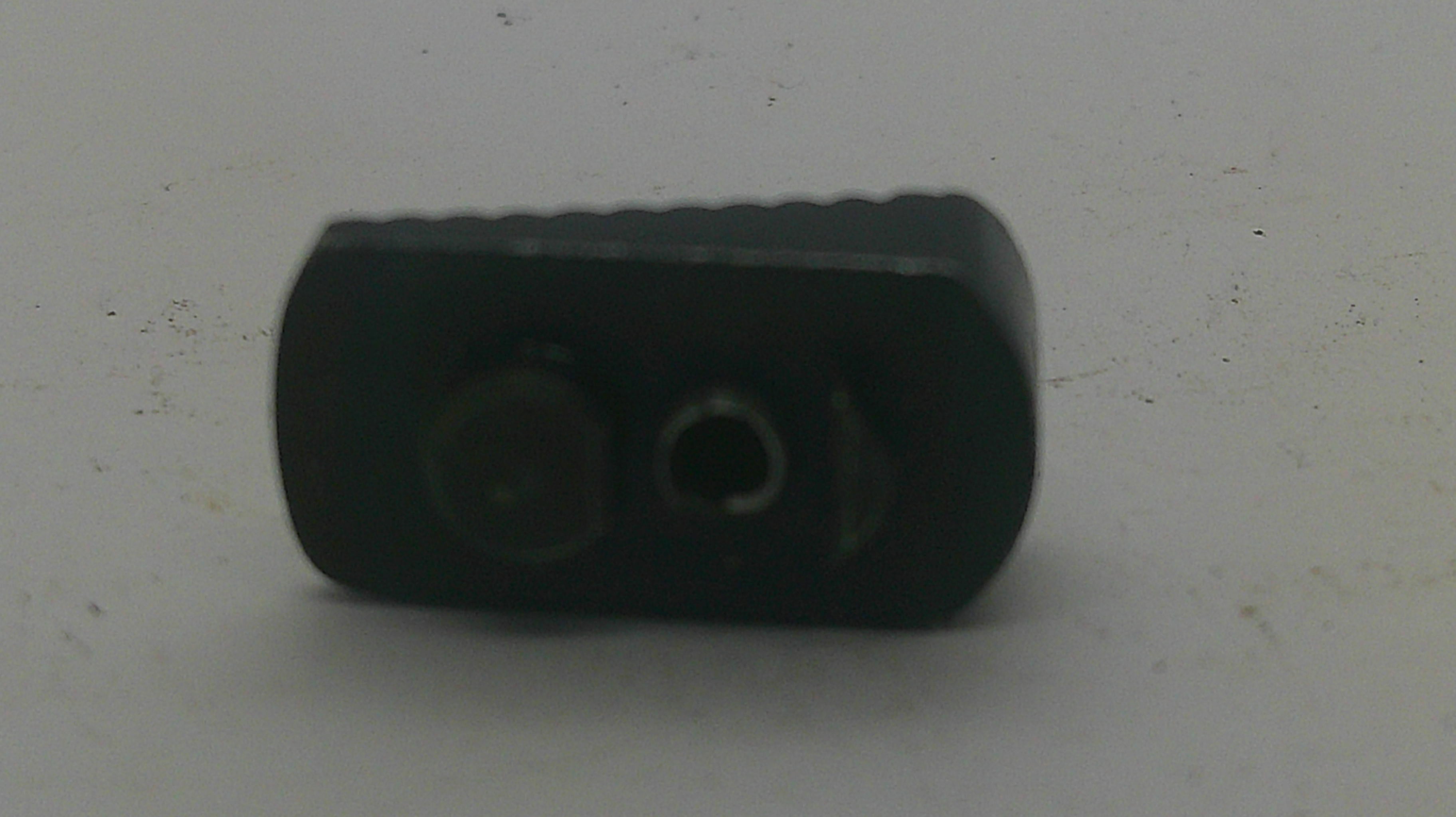 A small black plastic component with two circular openings, photographed on a plain light gray surface.