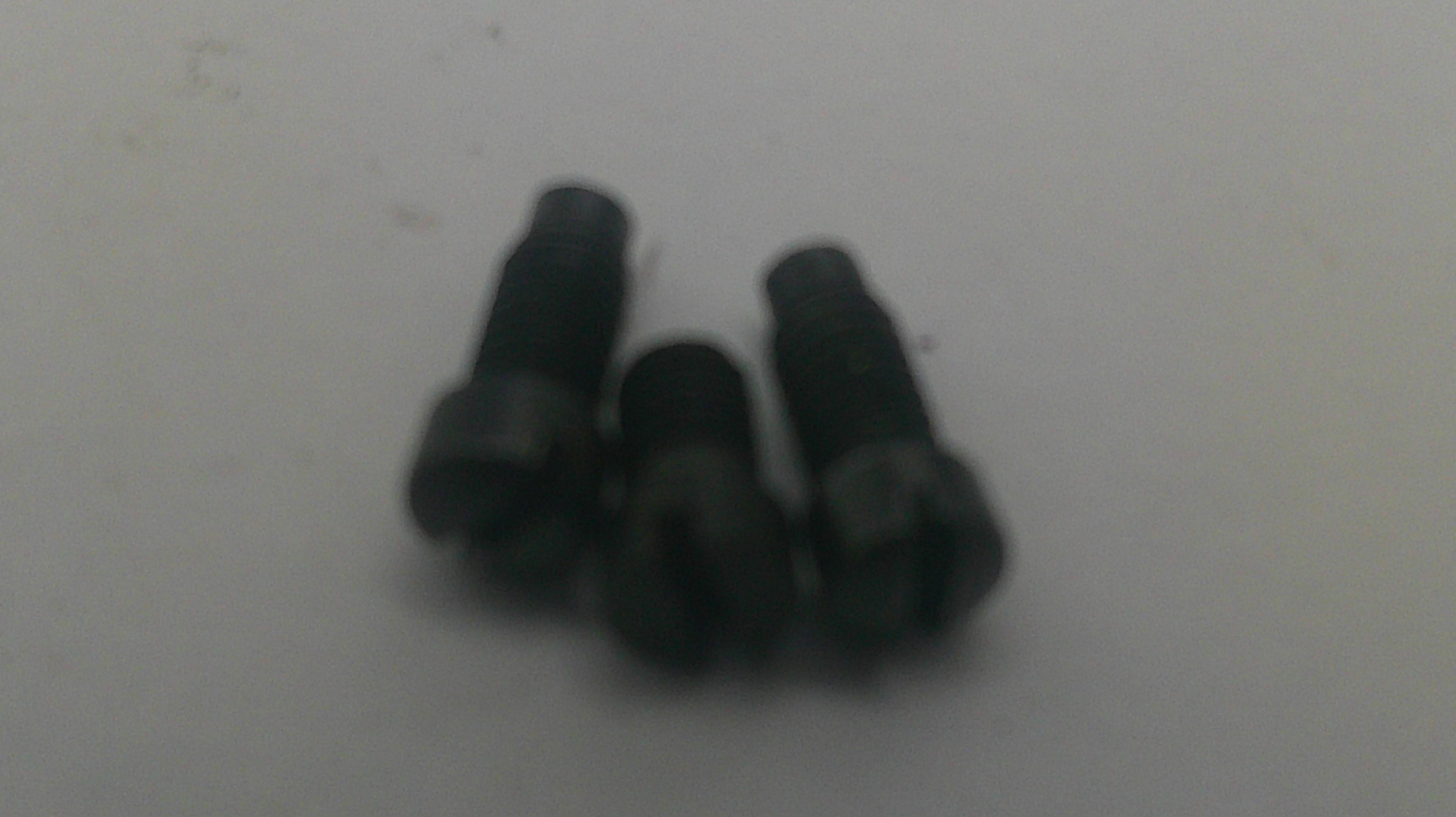 Three small black metal screws or rivets on a plain light gray background.