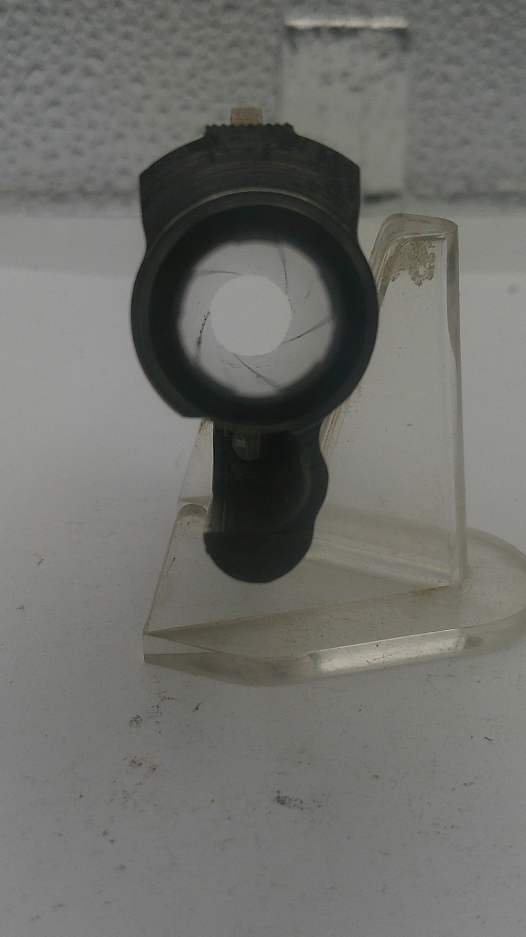 Clear plastic component with black cylindrical object on a white background